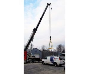 A truck with a crane attached to it is parked next to a van.