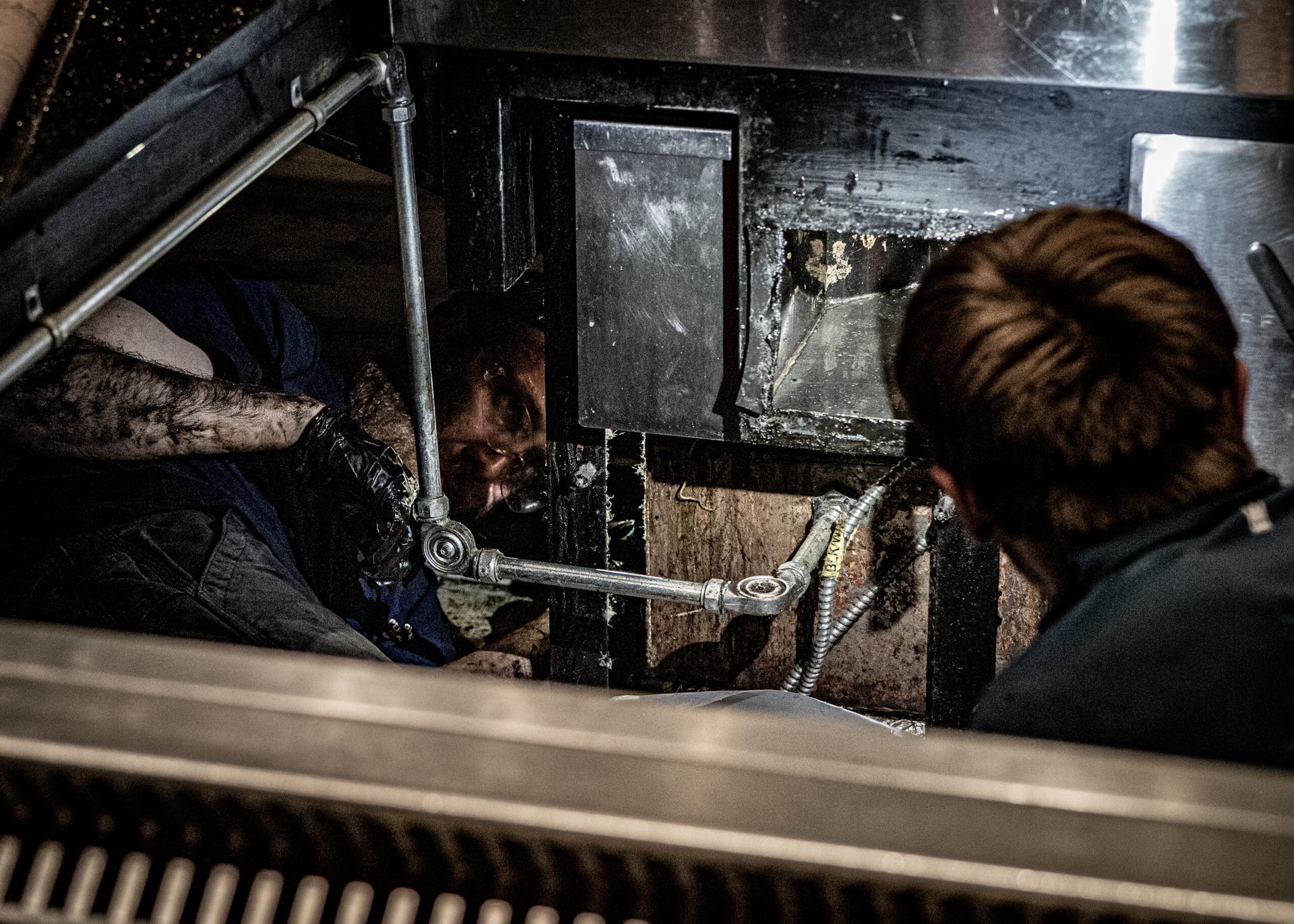 A Man Is Working on A Pipe in A Kitchen | S. Glens Falls, NY | Performance Industrial