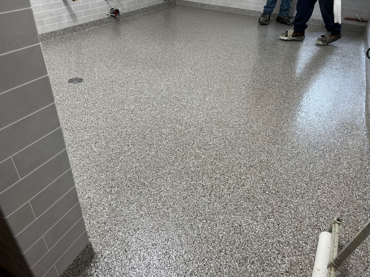 A person is standing on a concrete floor in a bathroom.