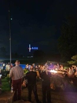 A group of people are standing in front of a pool at night.