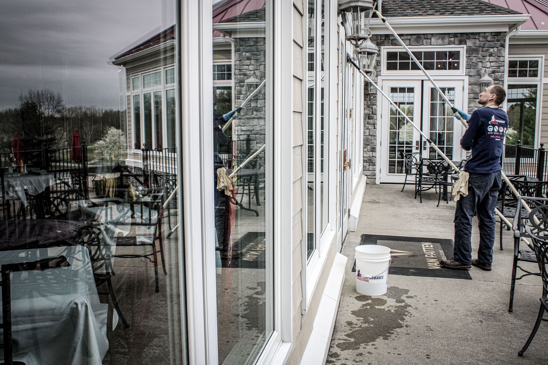 A man is cleaning the windows of a building with a high pressure washer.