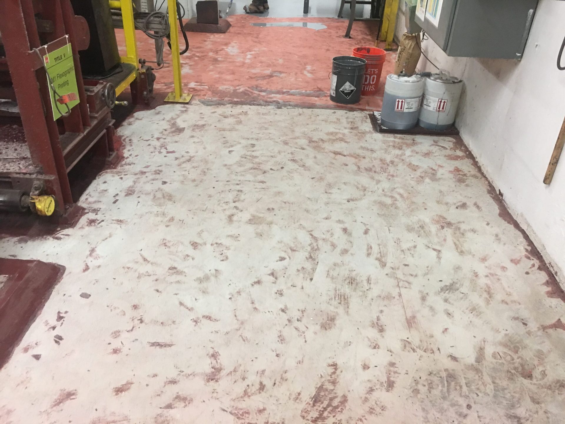 A dirty floor in a room with buckets of paint on it.