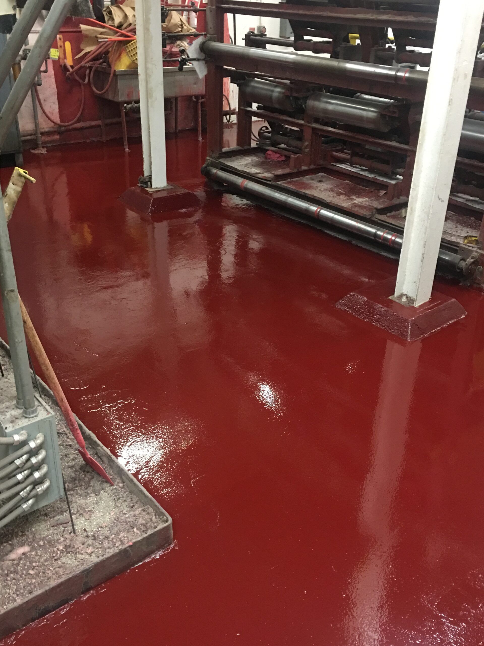 A red floor in a factory with pipes on it.
