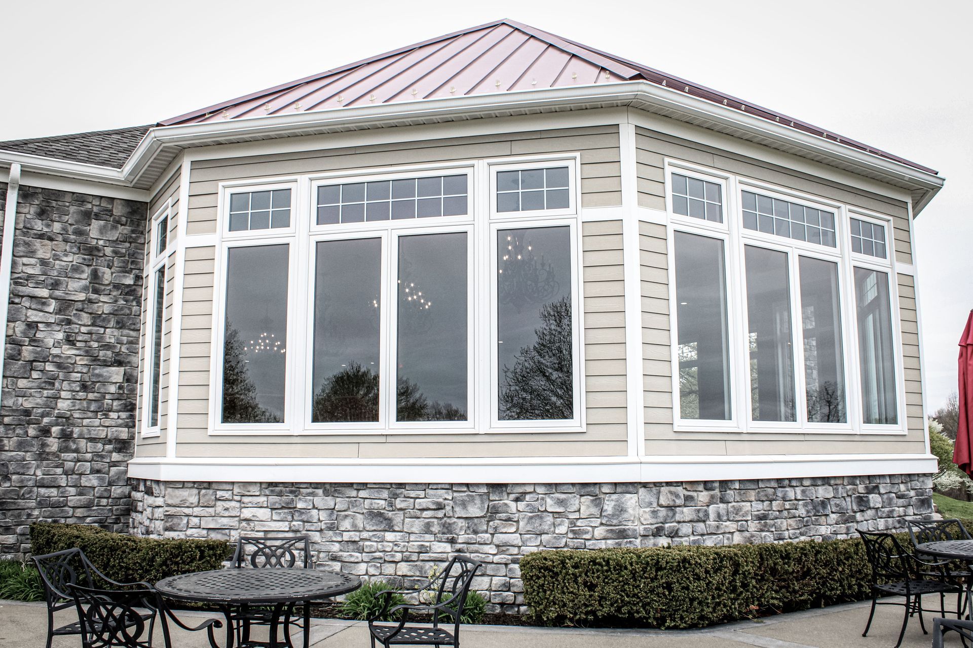 A large house with a lot of windows and tables and chairs in front of it.