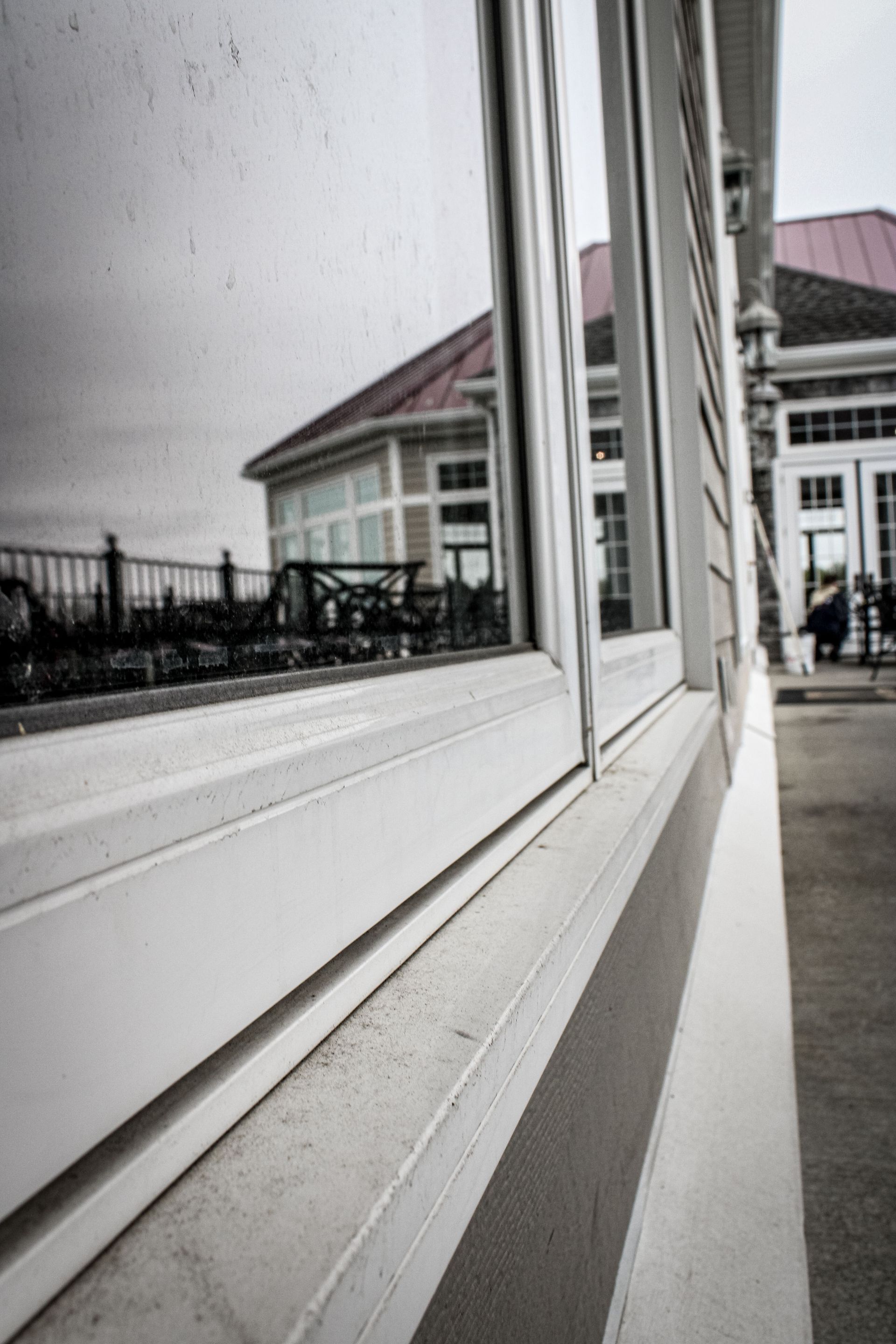 A black and white photo of a window with a reflection of a building