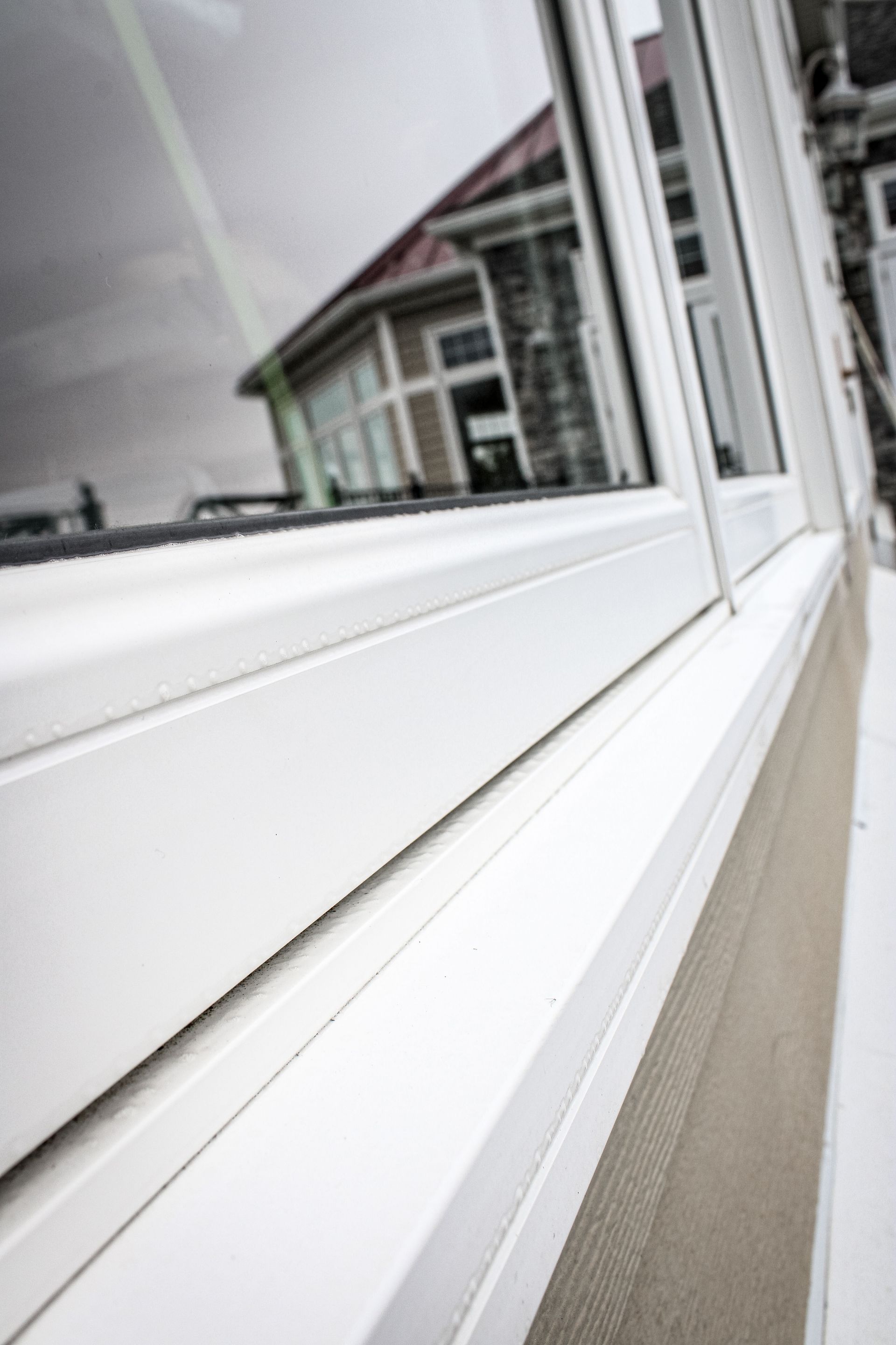 A close up of a white window with a house in the background.