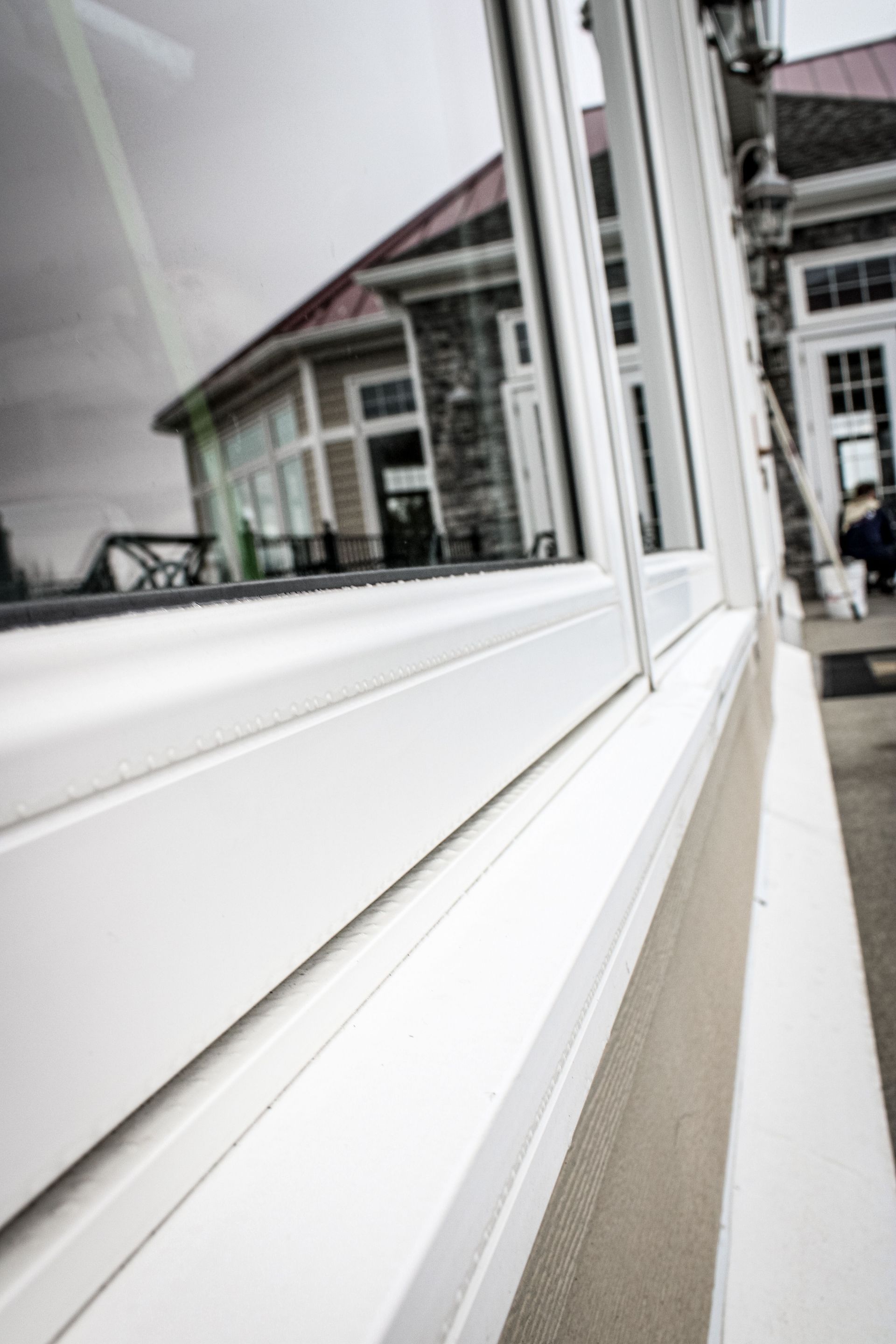 A white window with a reflection of a building in the window.