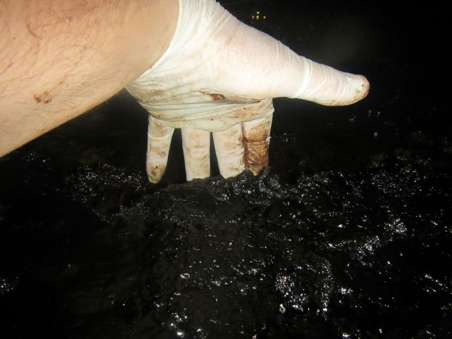 A person wearing a white glove is holding grease in their hand