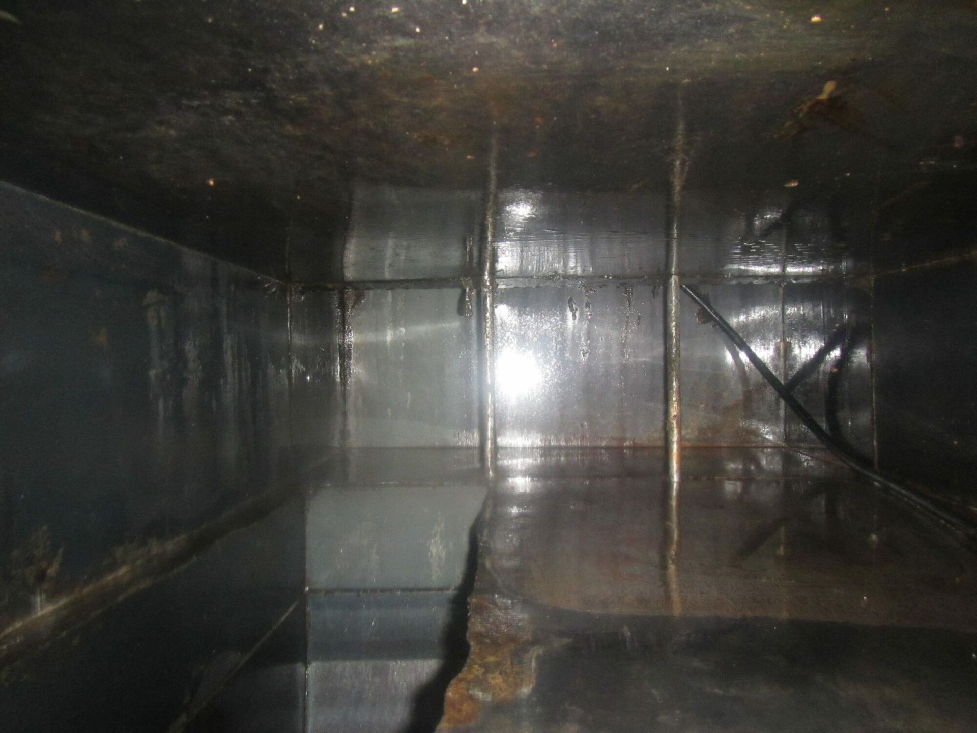 The inside of a large metal tank with water coming out of it.