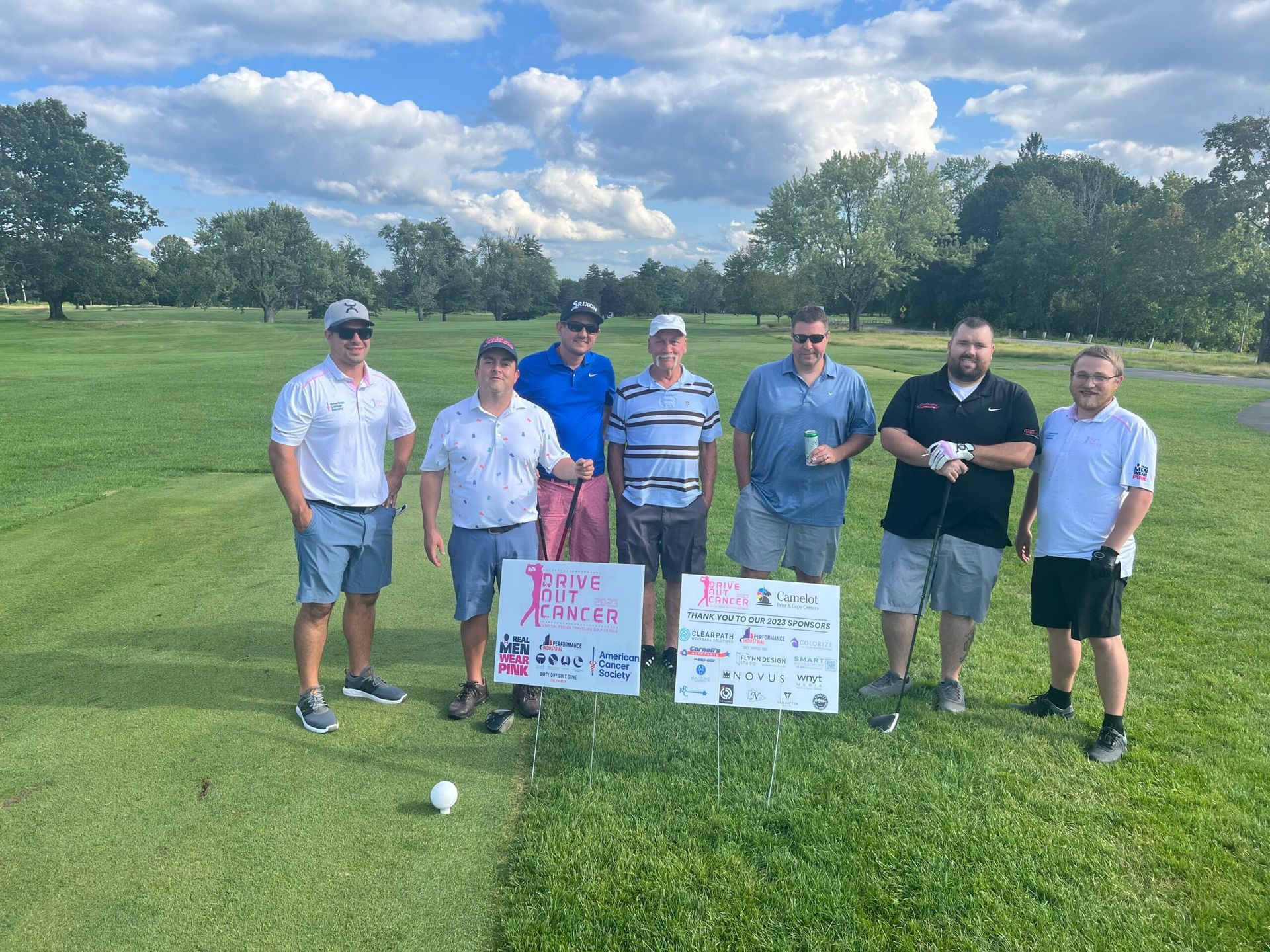A group of employee are posing for a picture on a golf course.
