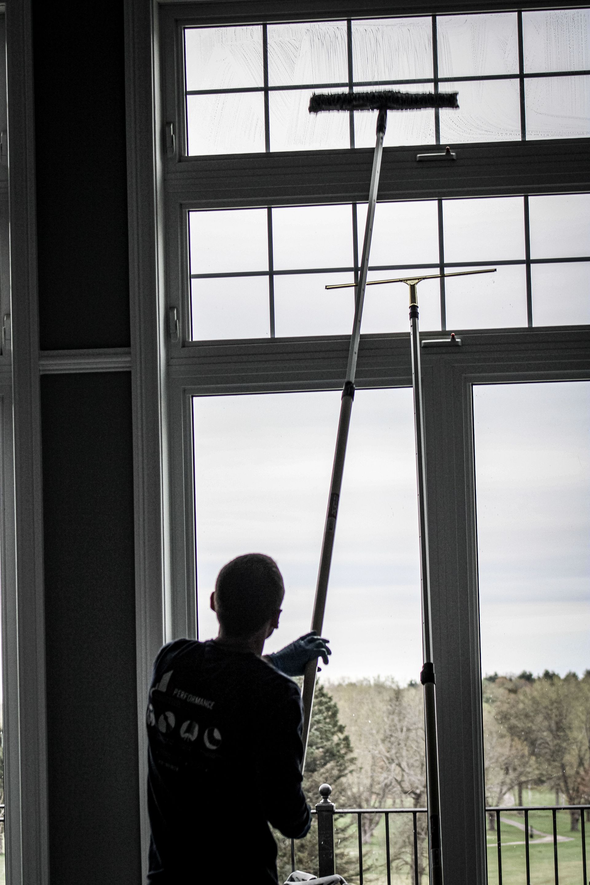 A man is cleaning a window with a long pole
