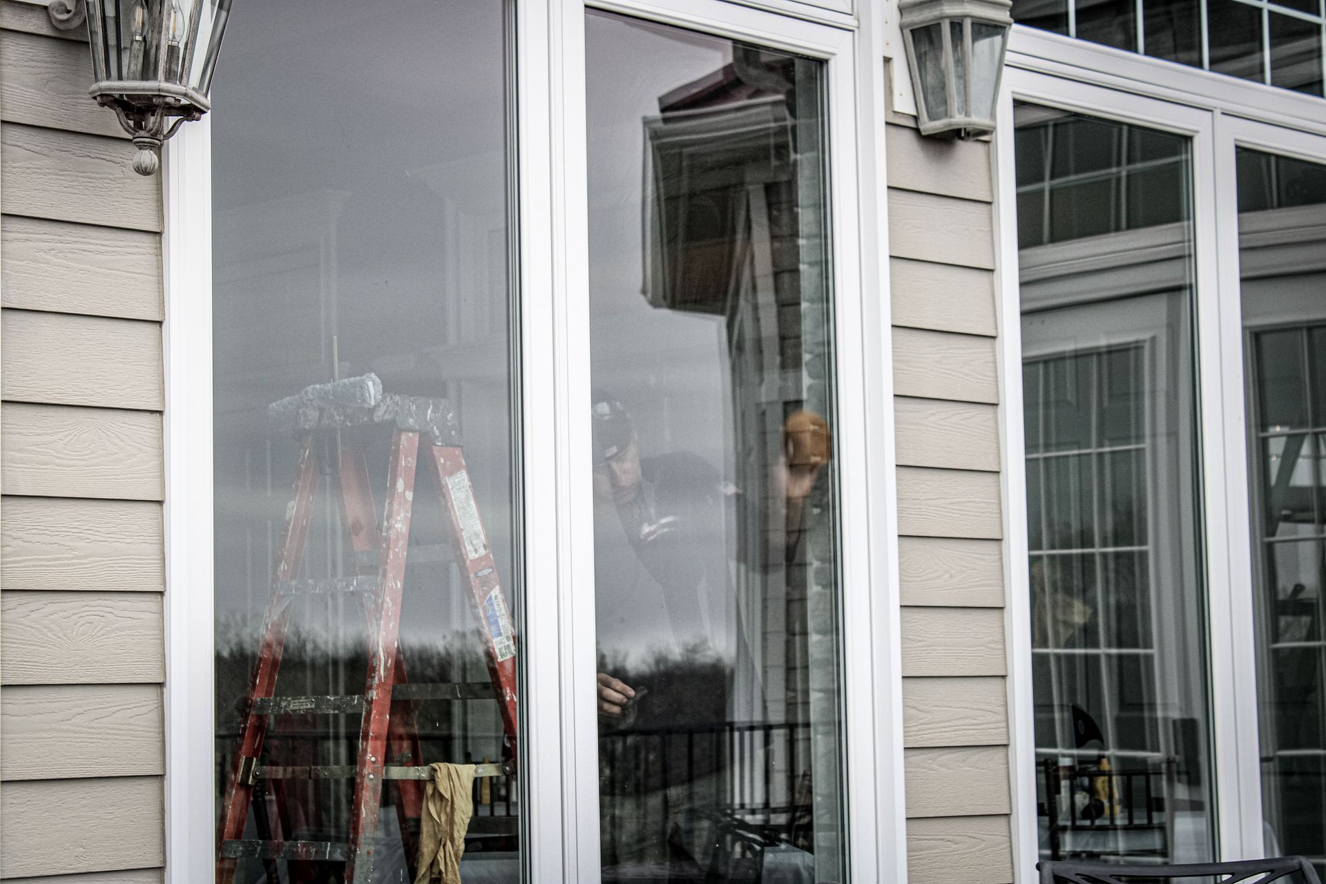 A ladder is sitting in front of a window on the side of a house.