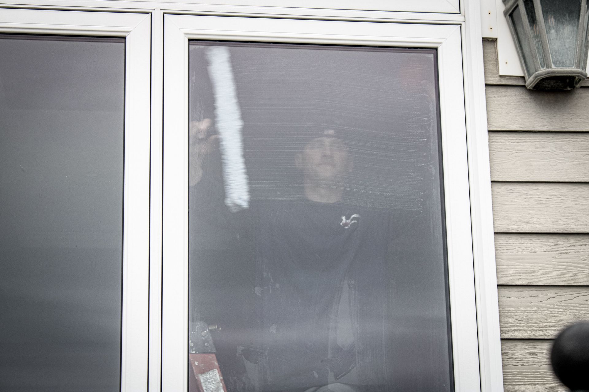 A man is standing in a window looking out.