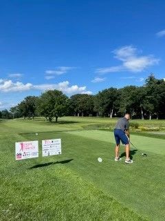 A man is swinging a golf club on a golf course.