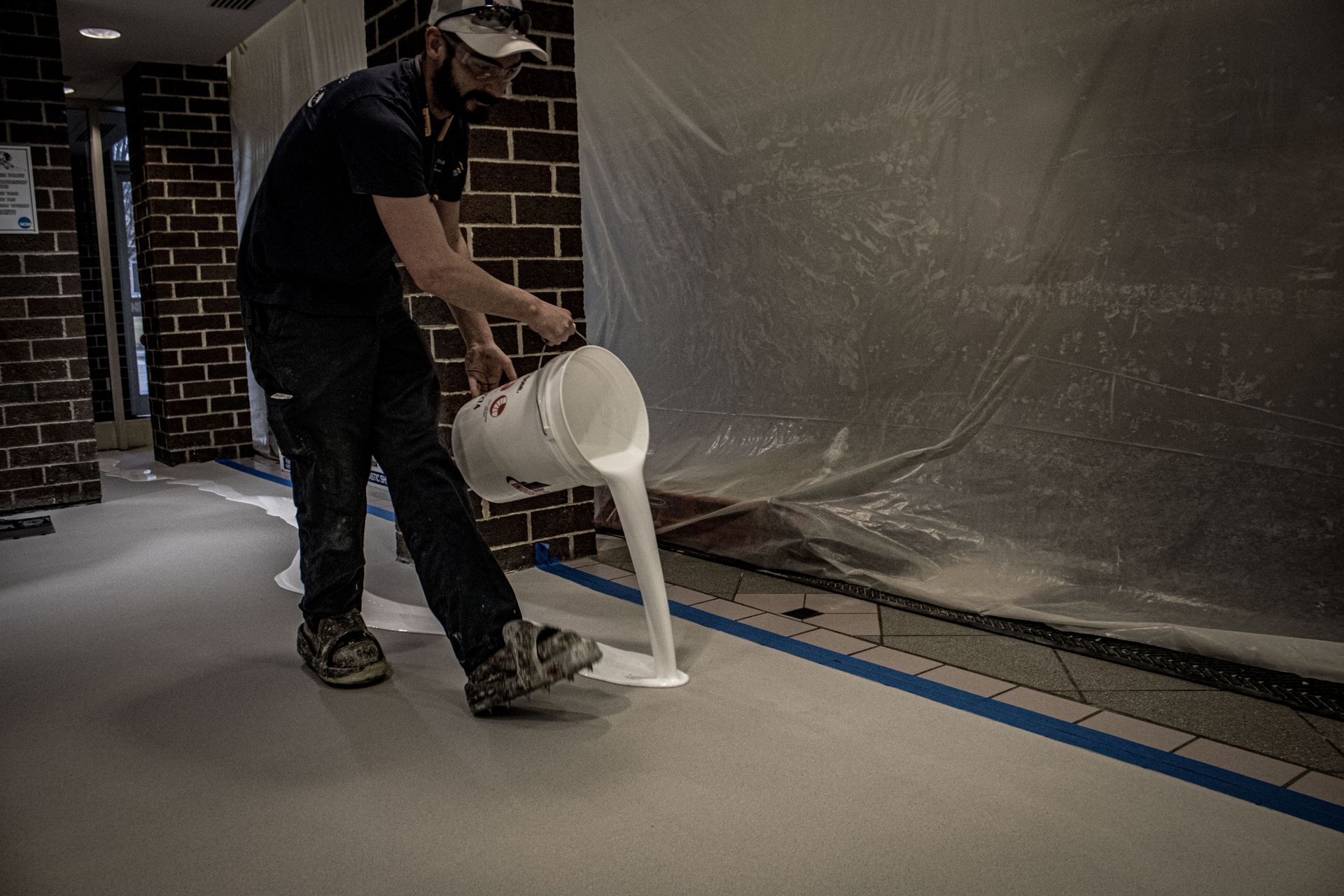 A man is pouring white paint into a hallway.