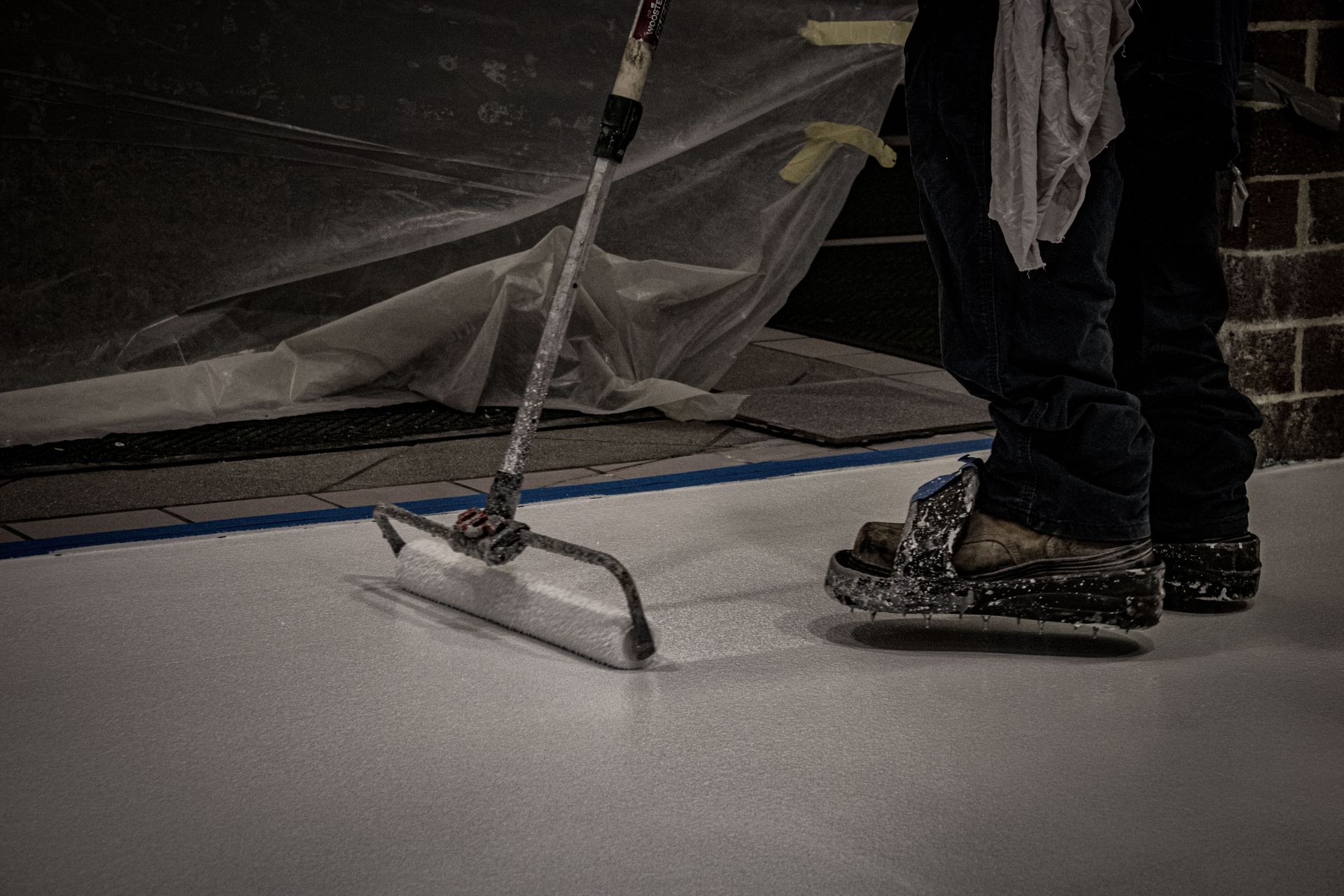 A person is painting a floor with a roller.