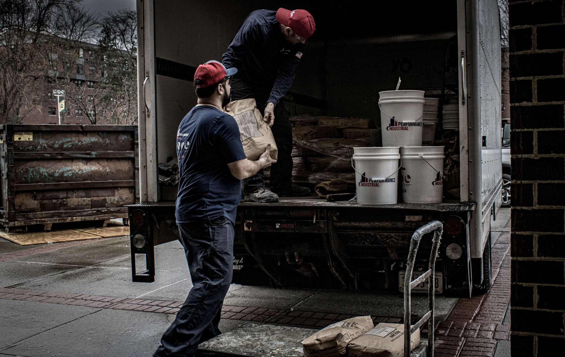 Two men are loading bags into a truck.