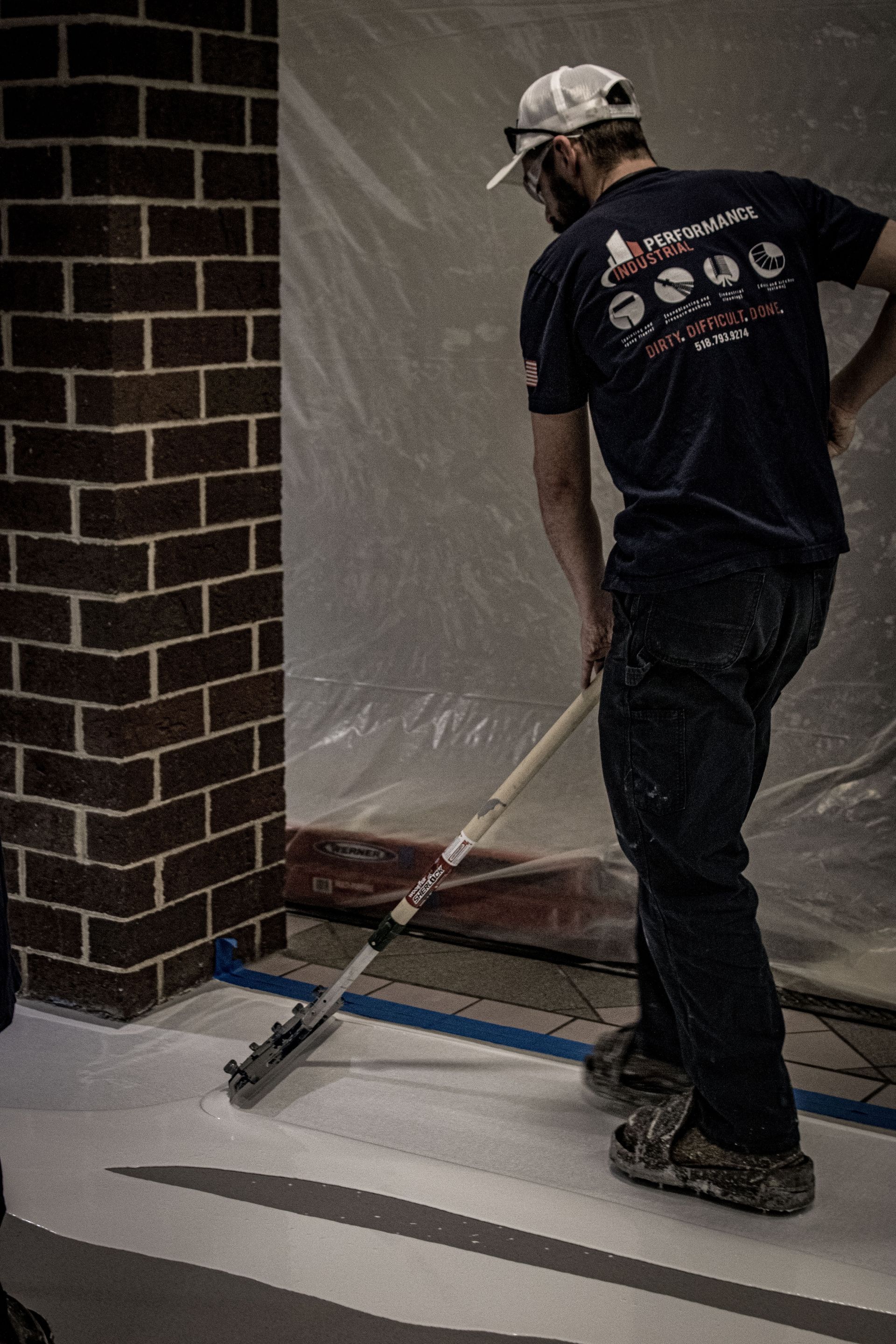 A man is painting a brick wall with a broom.