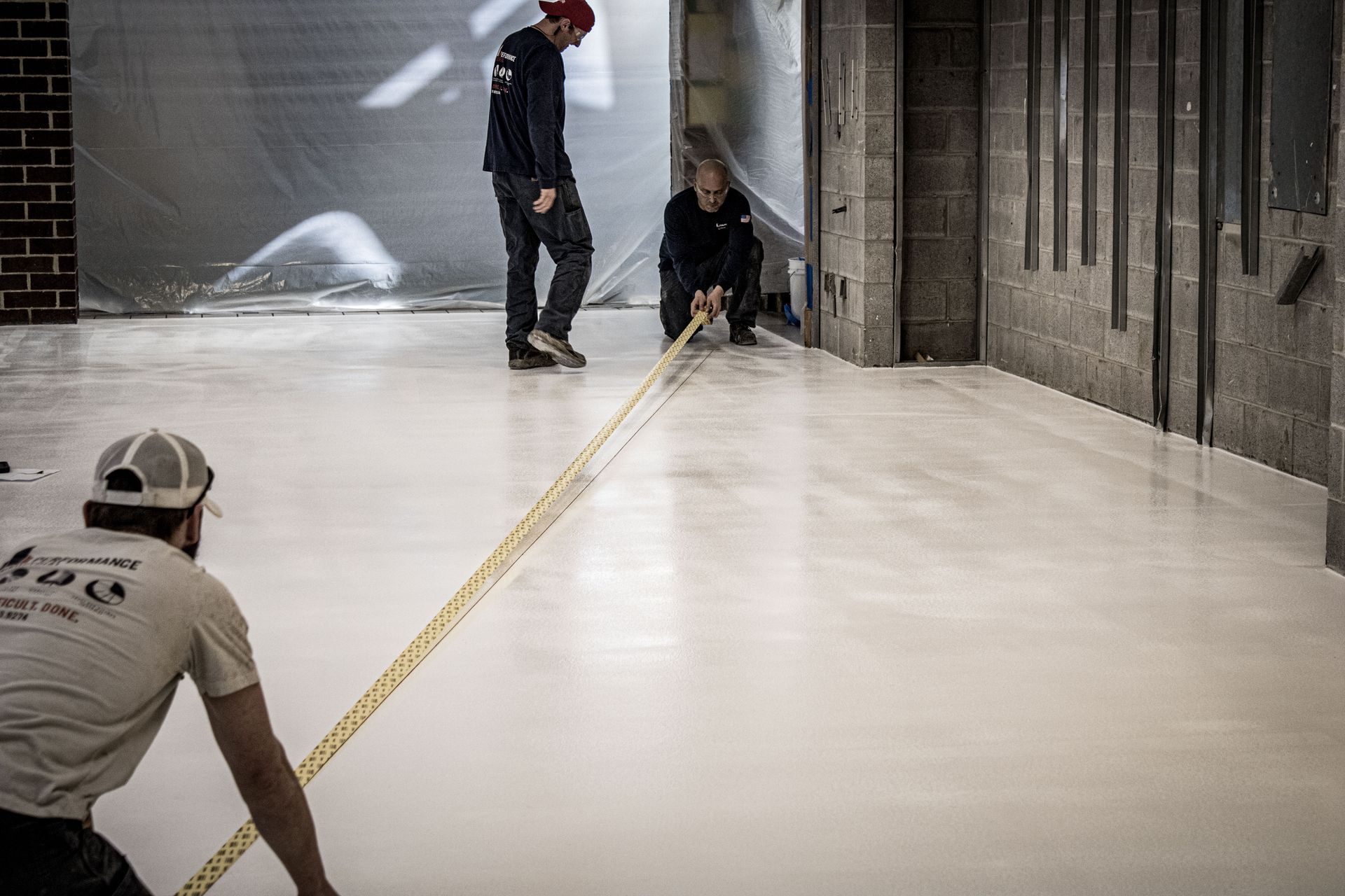 Two men are measuring a white floor with a tape measure.