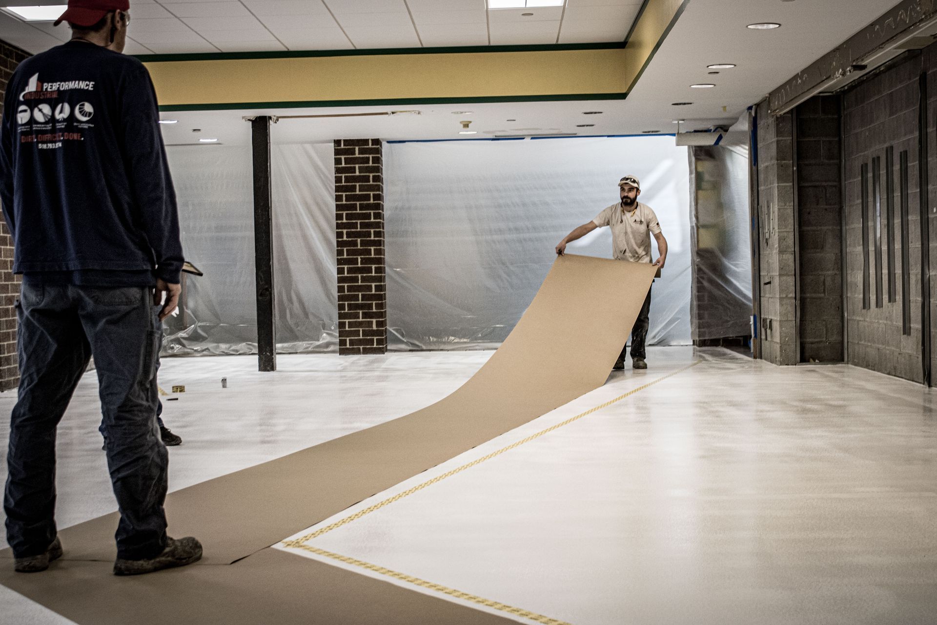 A man is carrying a large piece of cardboard in a room.