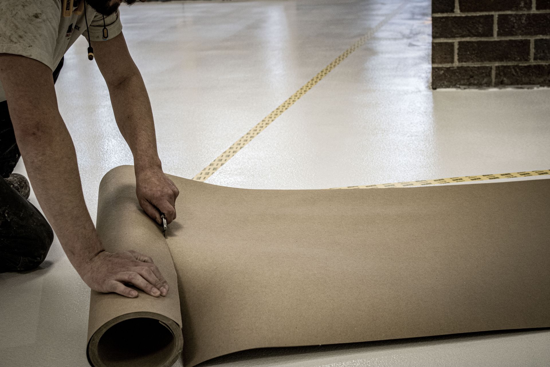 A man is measuring a roll of cardboard with a tape measure.