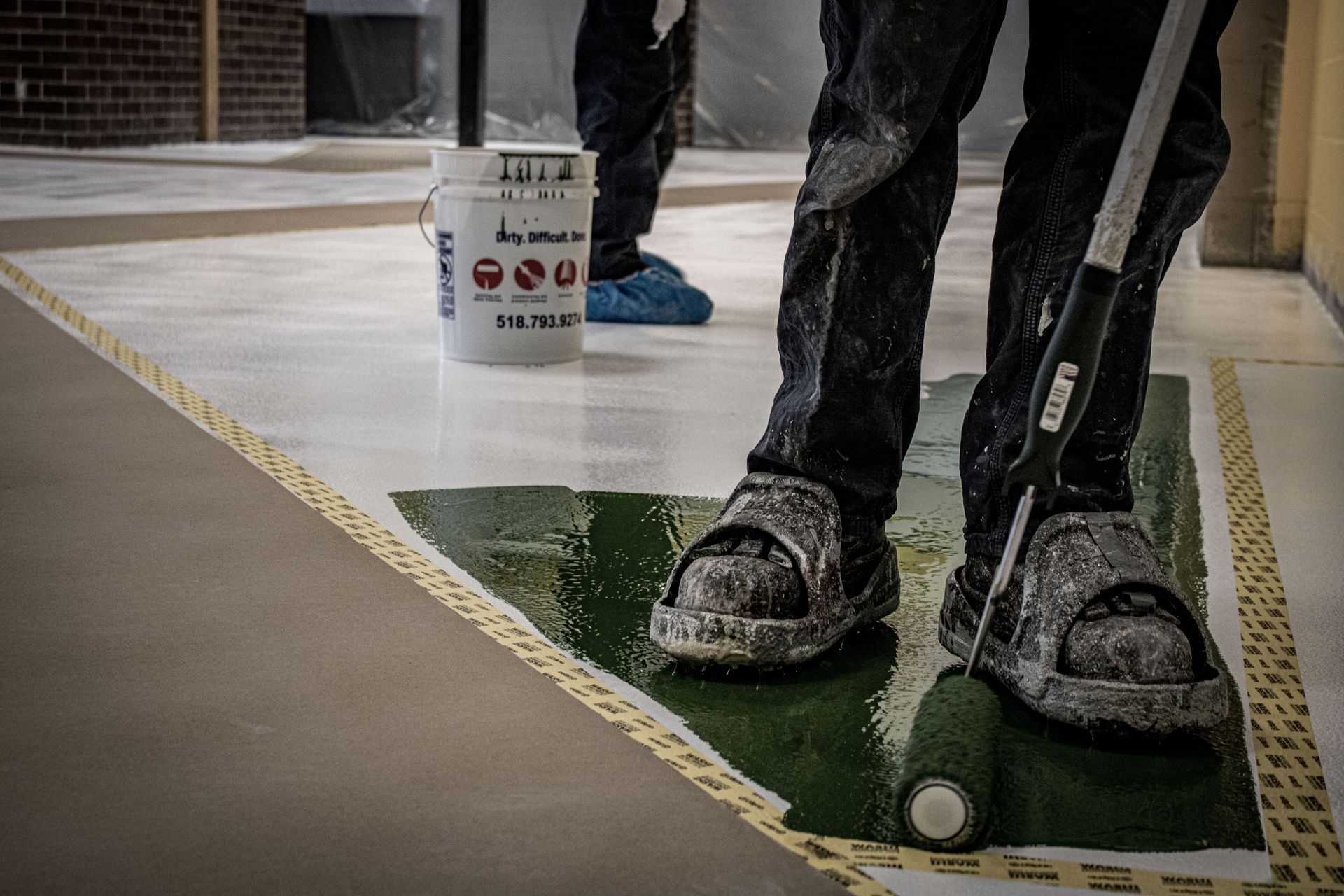 A person is painting a floor with a roller.