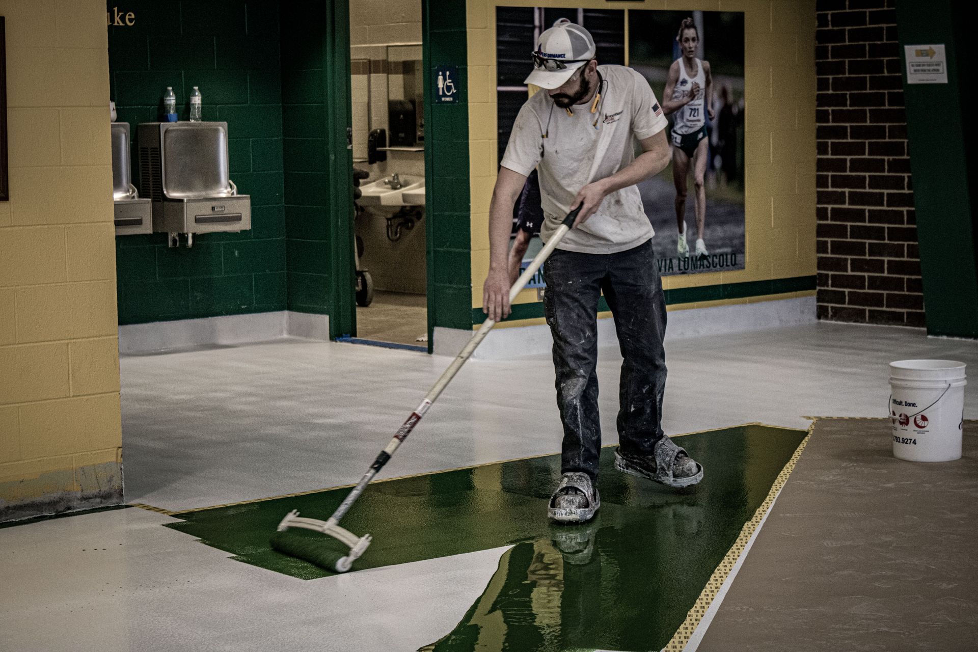 A man is painting a floor with a roller.