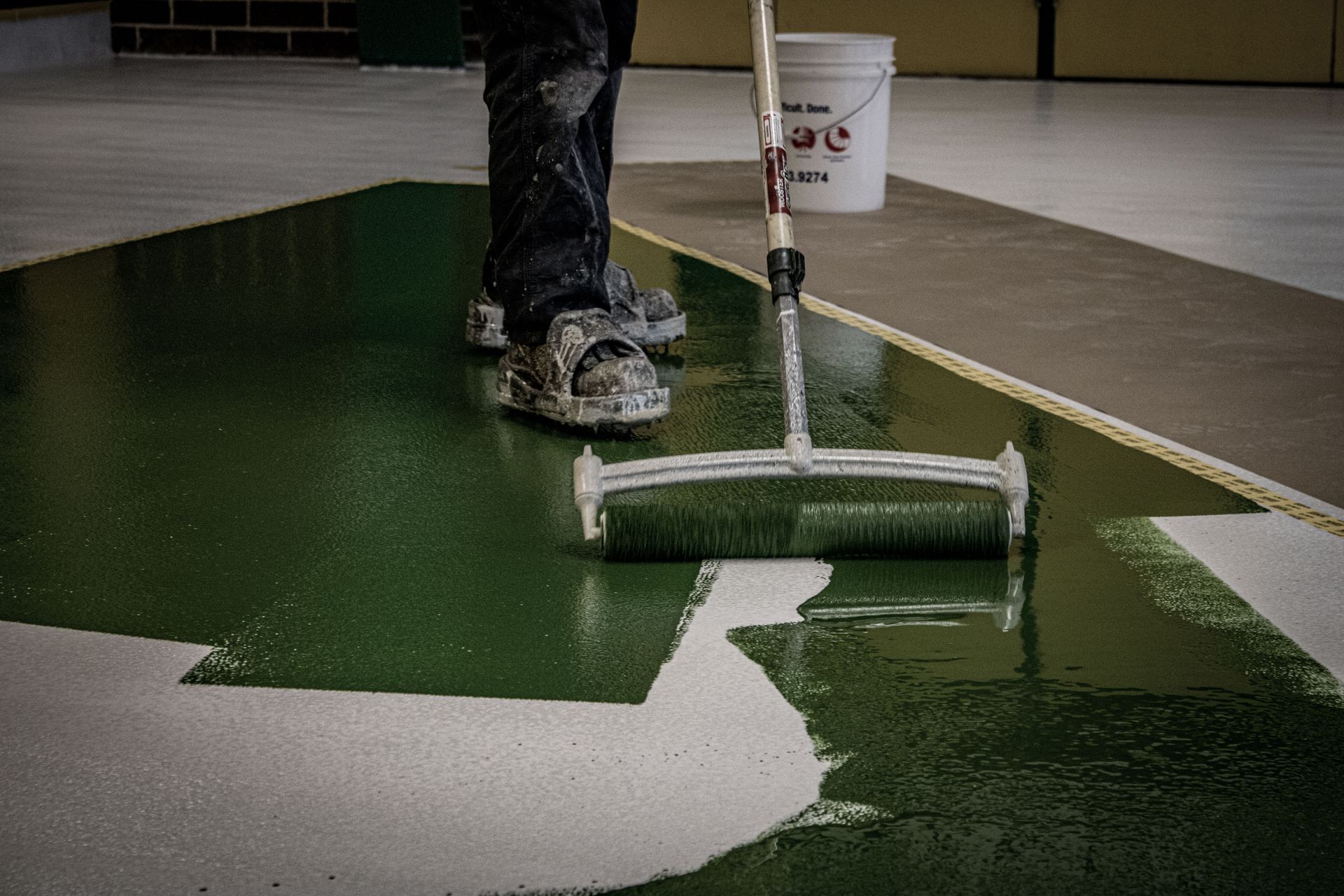 A person is painting a floor with a roller.