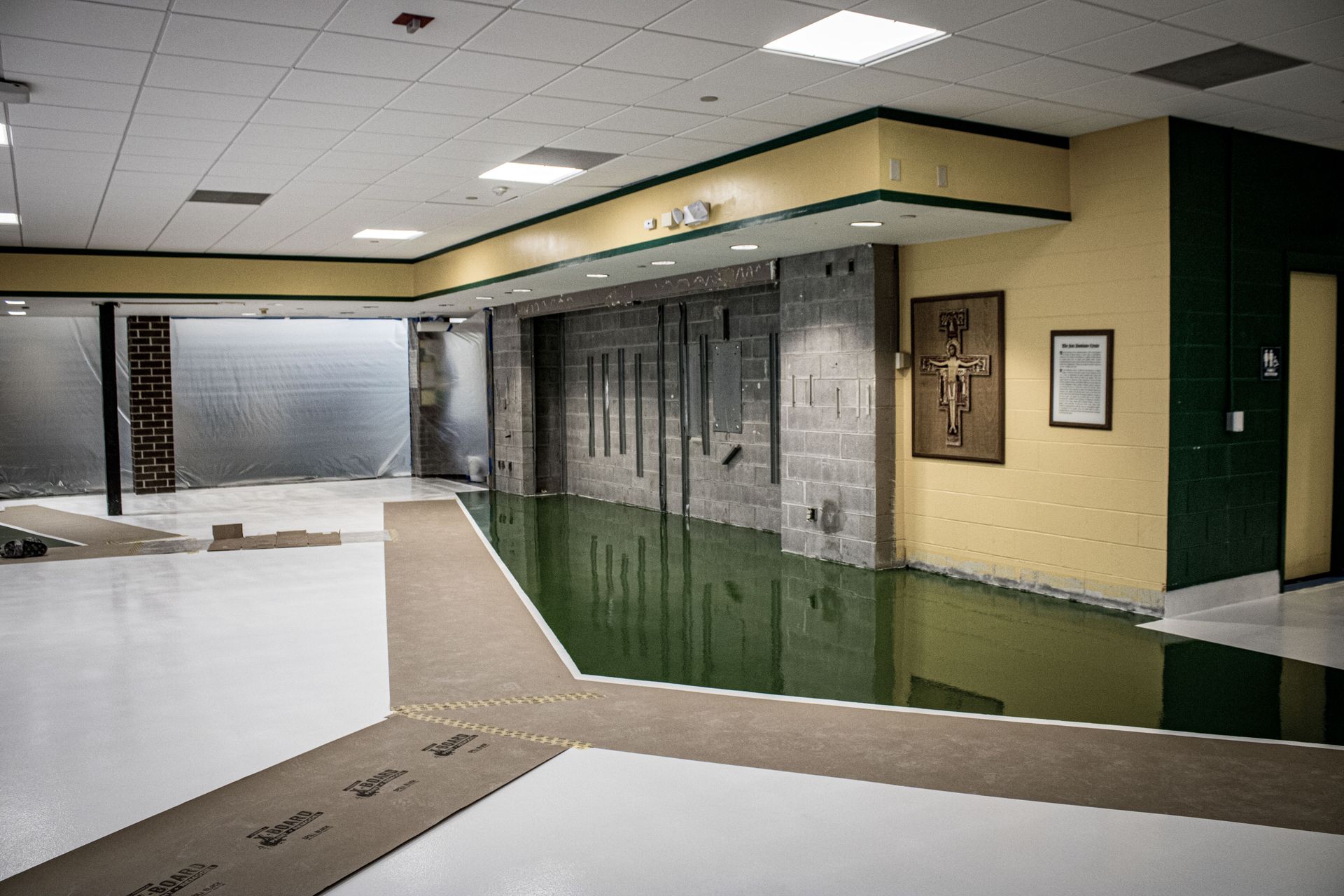 An empty room with a green floor and a cross on the wall