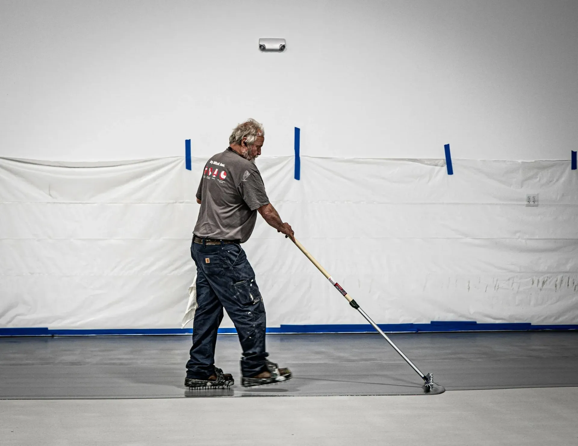 A Man Is Painting the Floor of A Building with A Roller | S. Glens Falls, NY | Performance Industrial