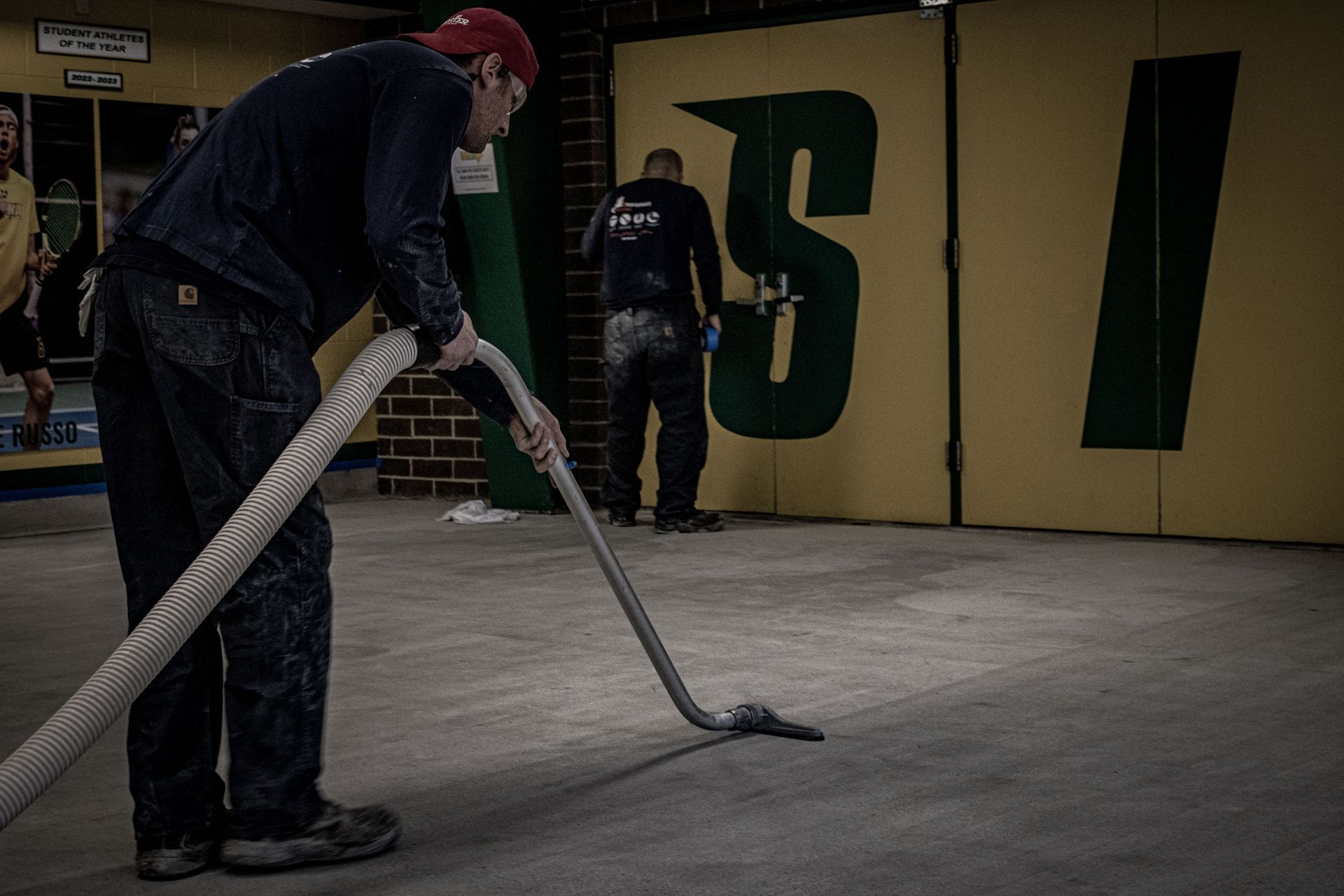 A man is using a vacuum cleaner to clean a concrete floor