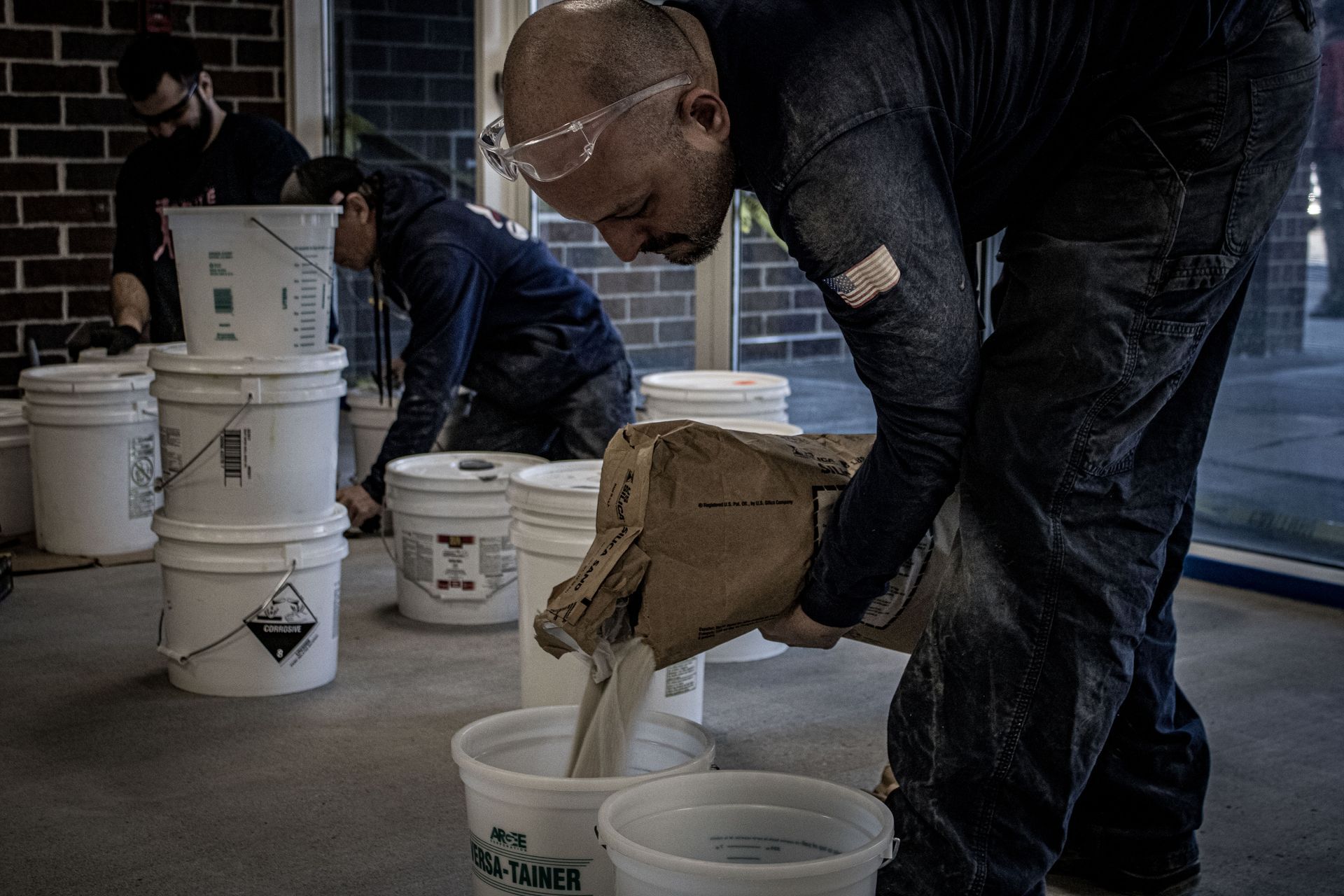 A man is pouring liquid into a plastic bucket.