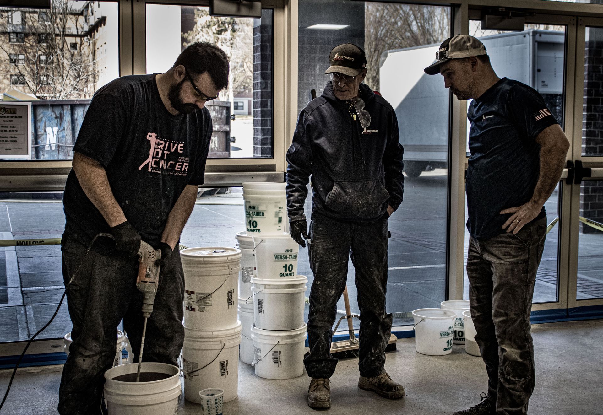 Three men are working in a room with buckets of paint