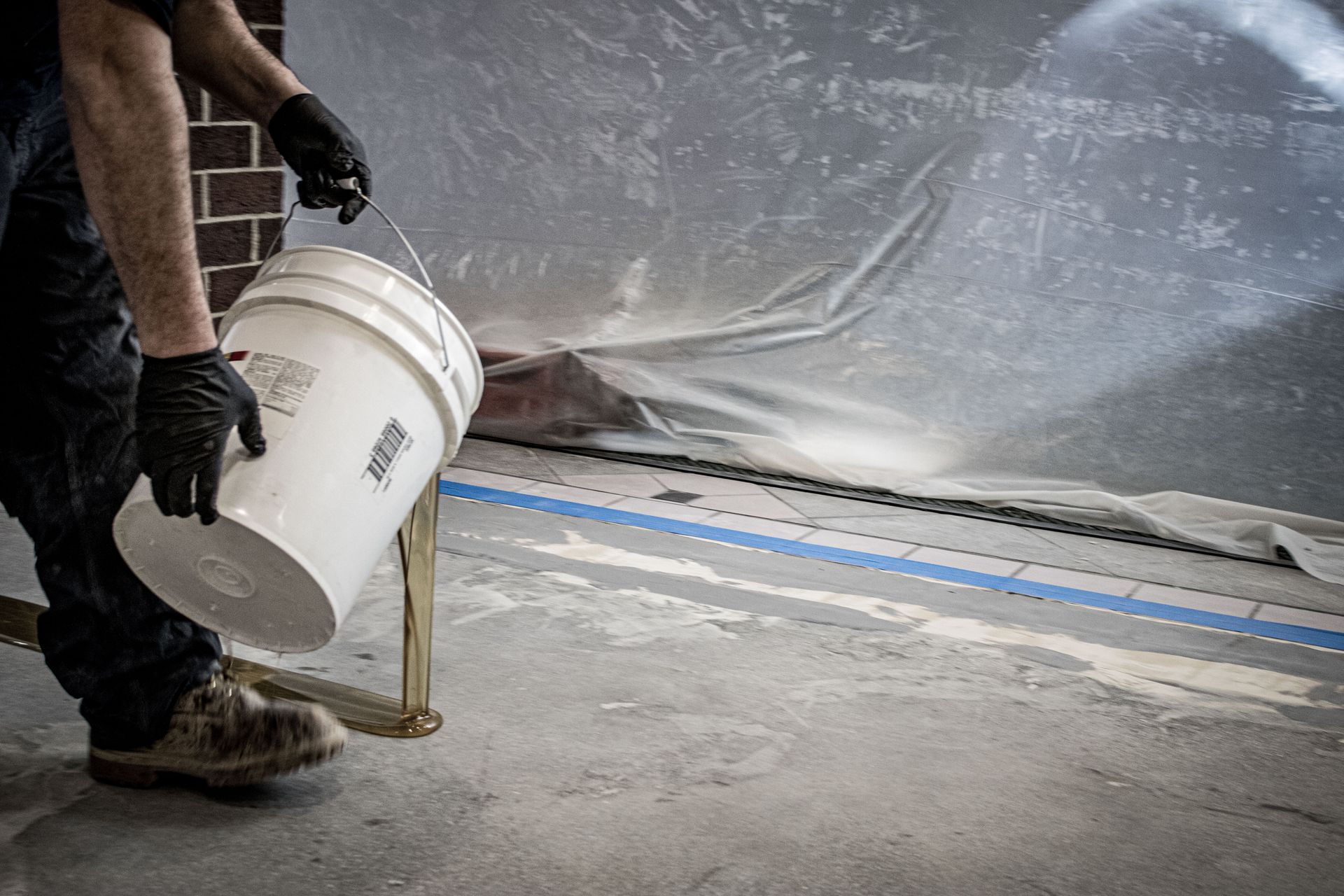 A man is pouring paint into a bucket.