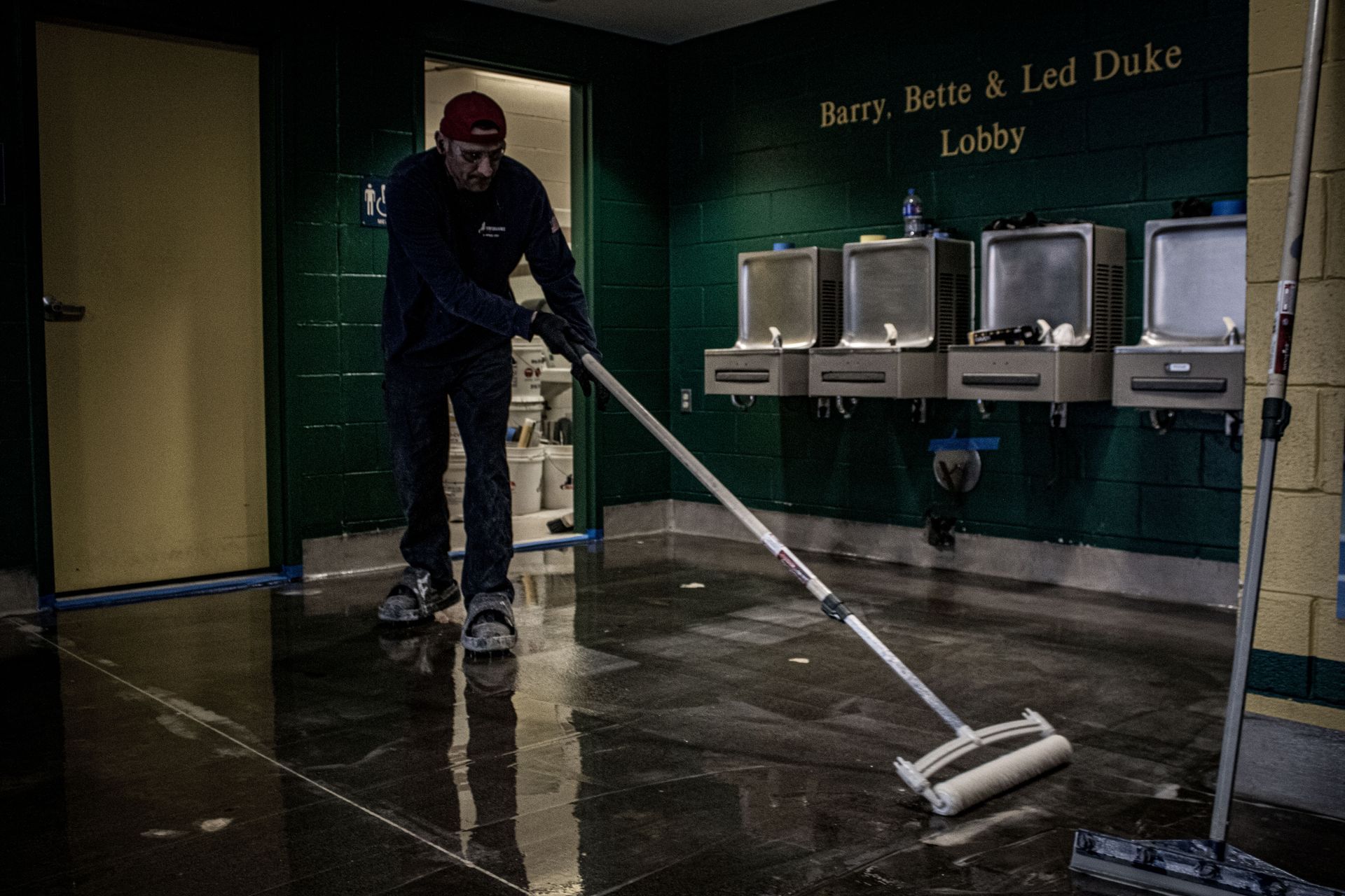 A man is cleaning the floor of a building with a mop.