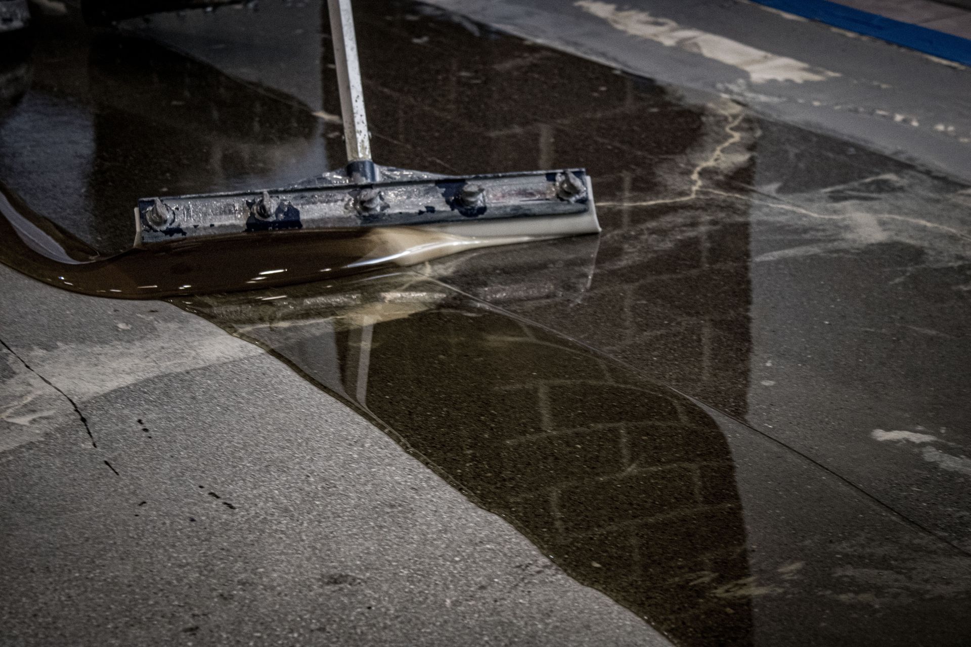 A person is cleaning a wet floor with a mop.