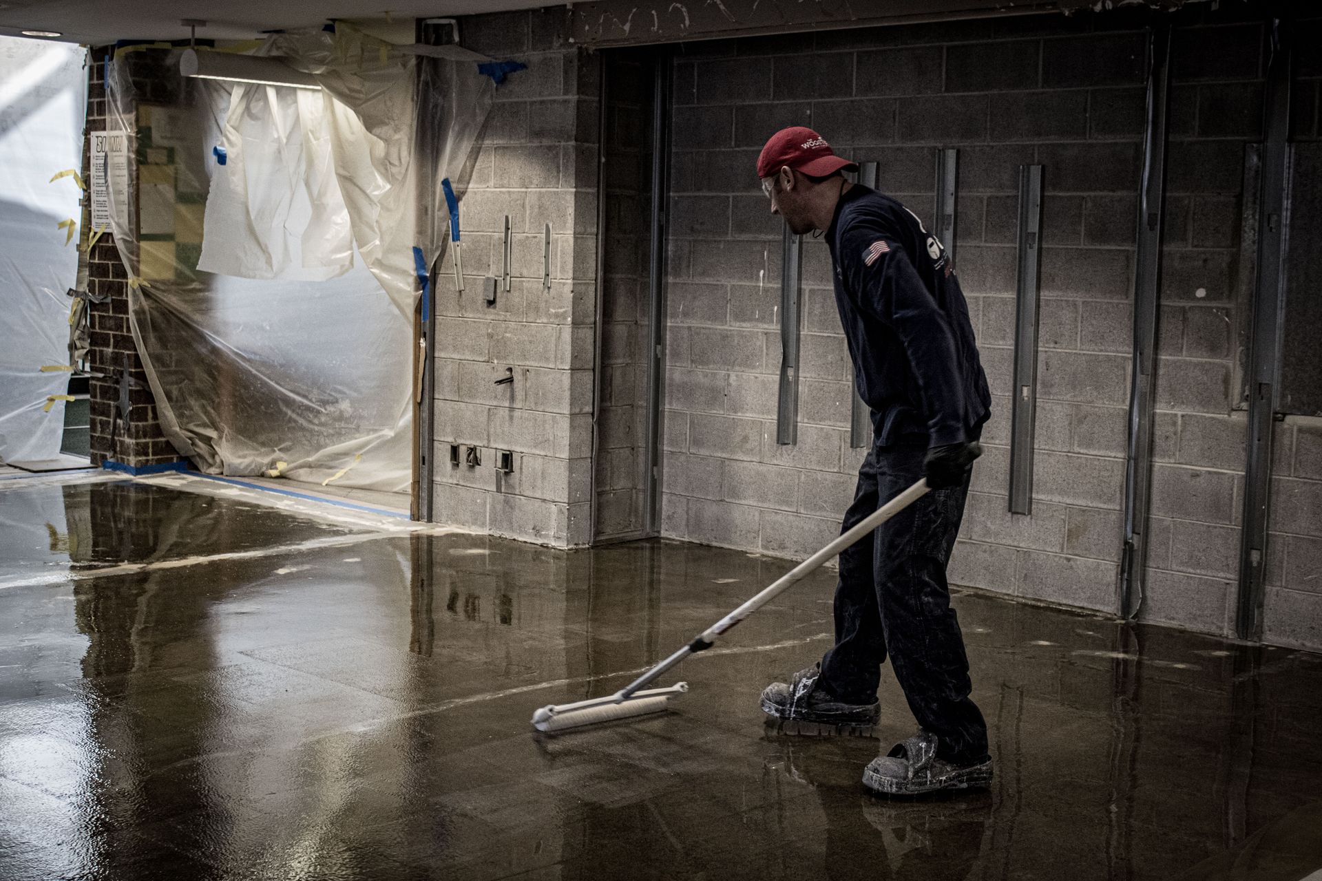 A man is cleaning the floor of a basement with a mop.