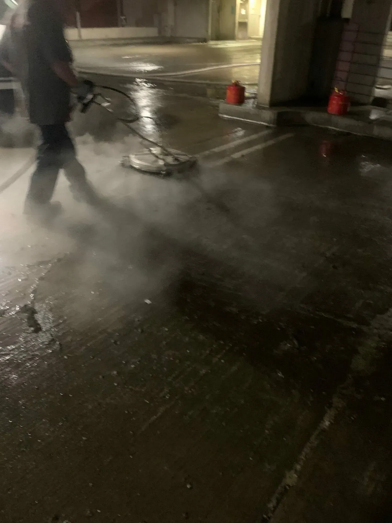 A man is using a pressure washer to clean a parking lot.
