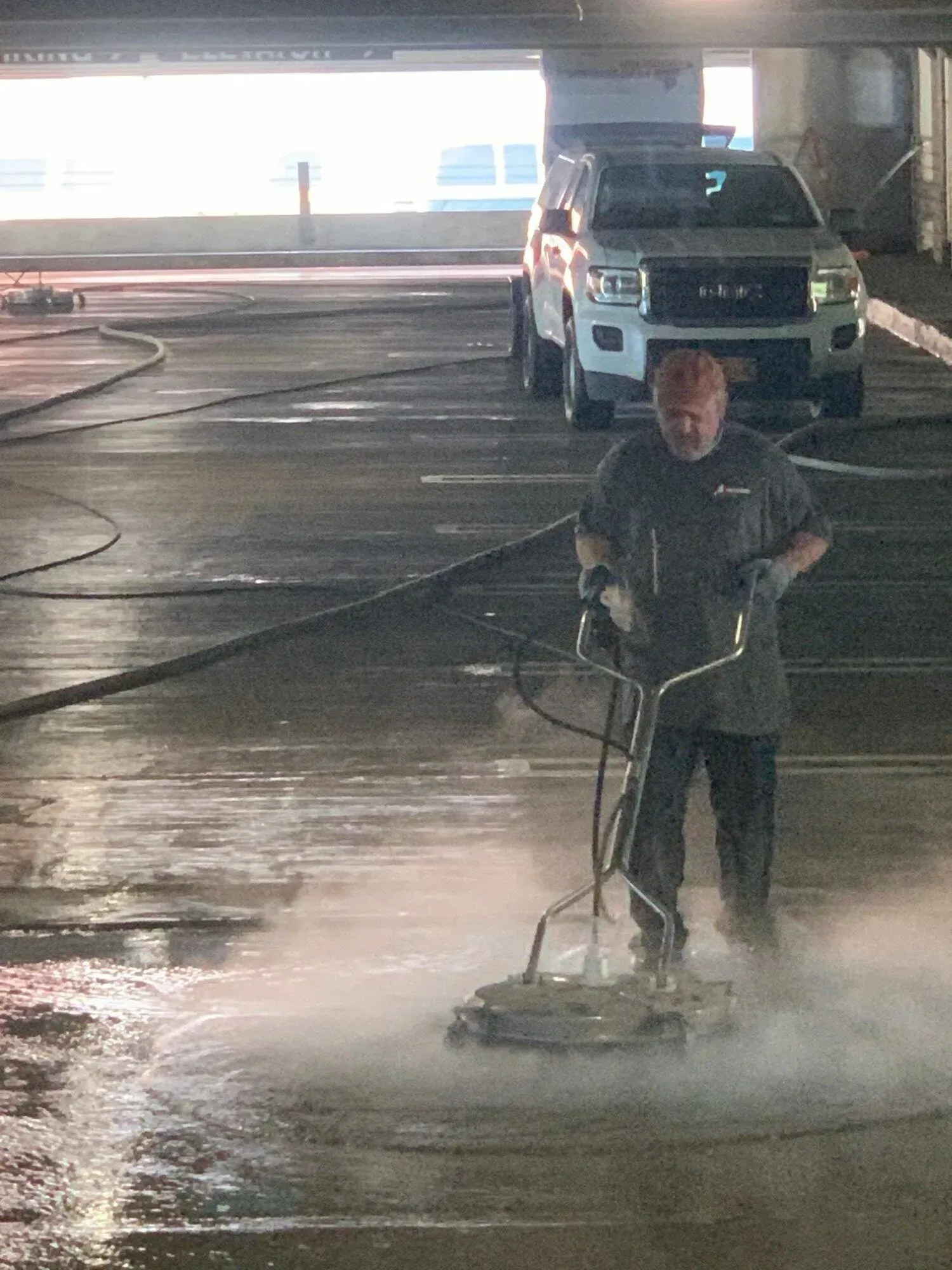 A man is using a machine to clean a parking lot.
