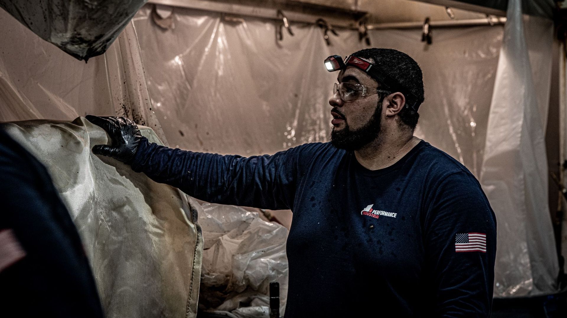 A man with a beard is standing next to a piece of plastic.