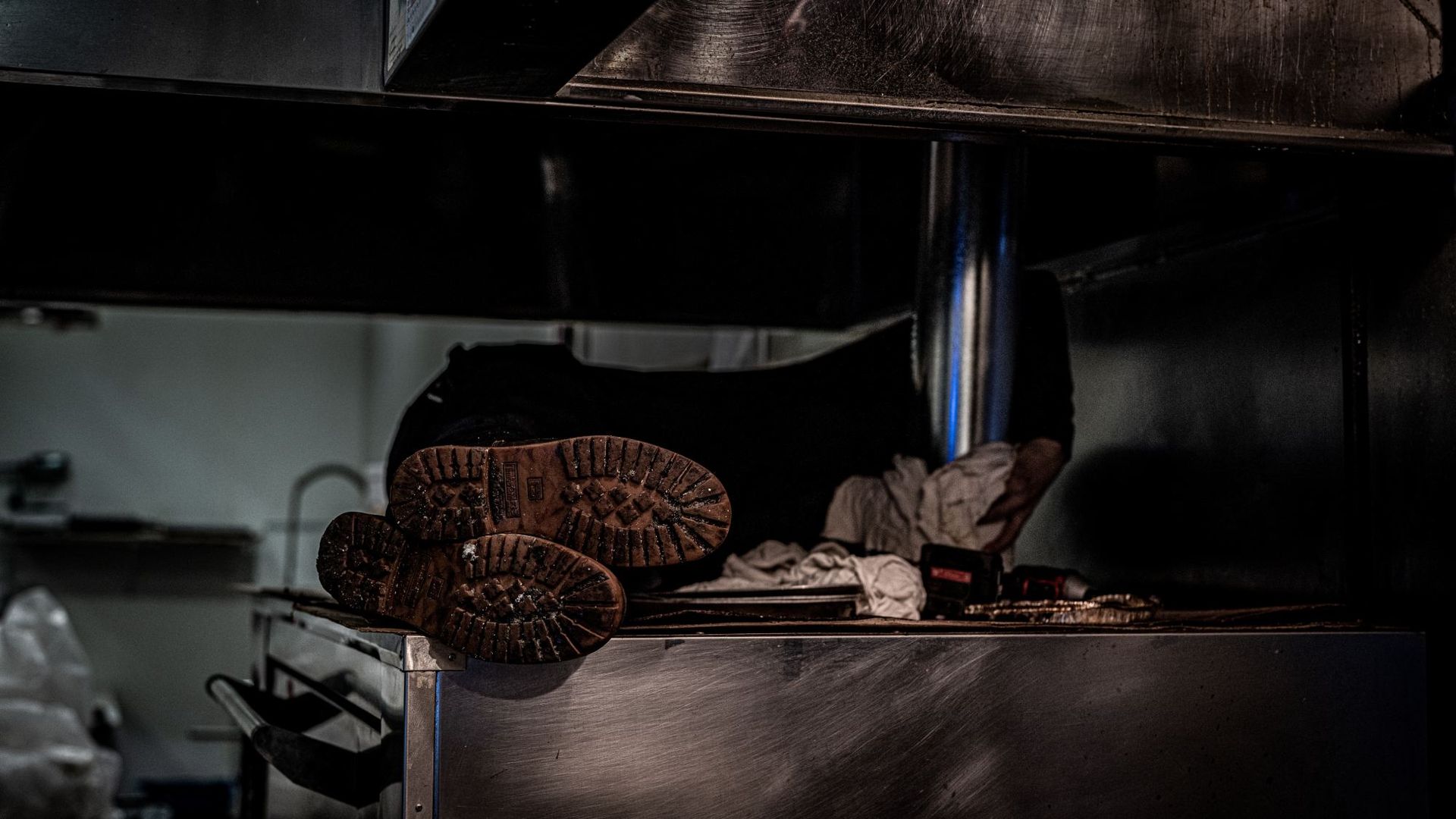 A person 's feet are sticking out of a stove in a kitchen.