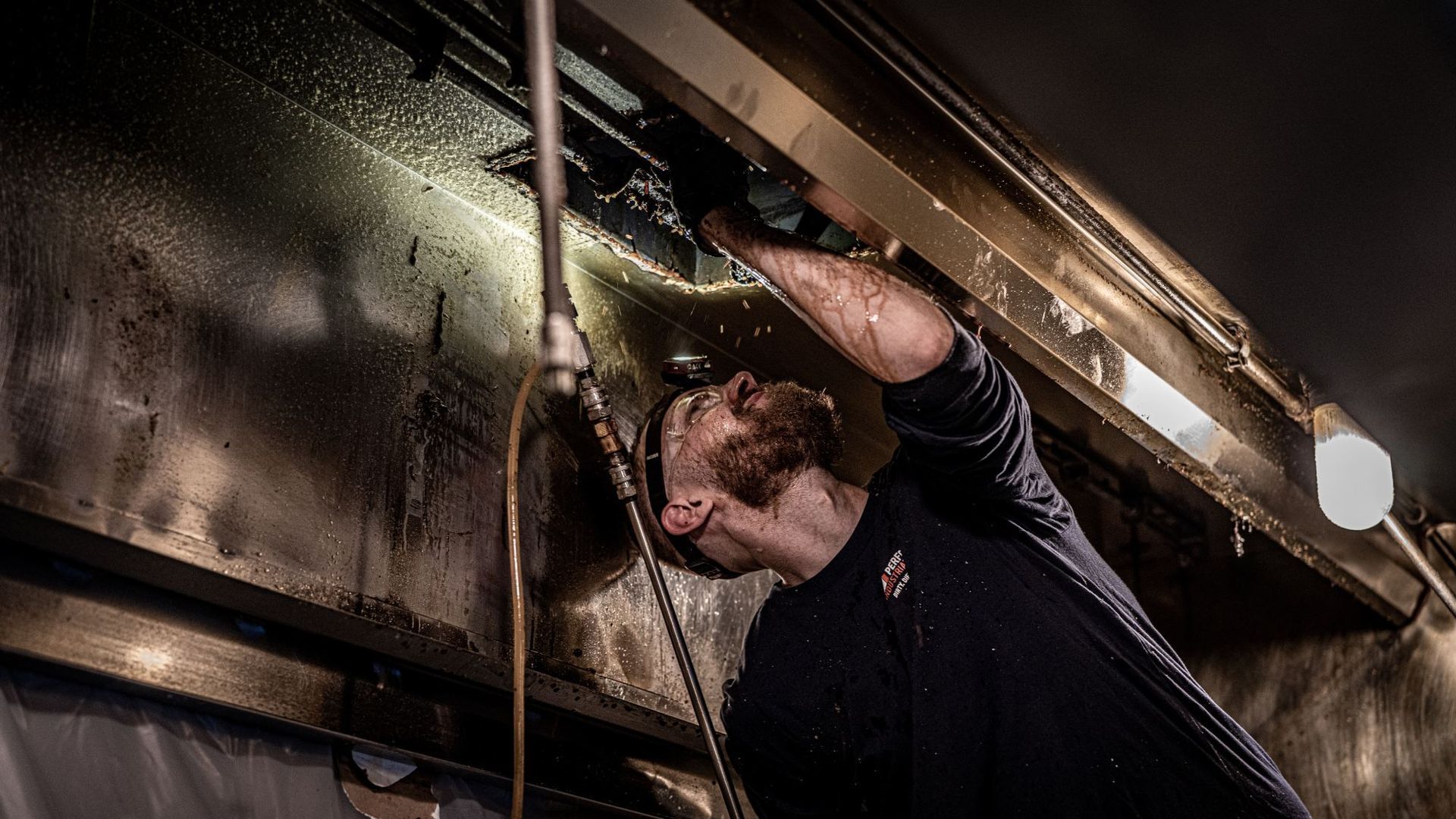 A man is working on a pipe in a dark room.