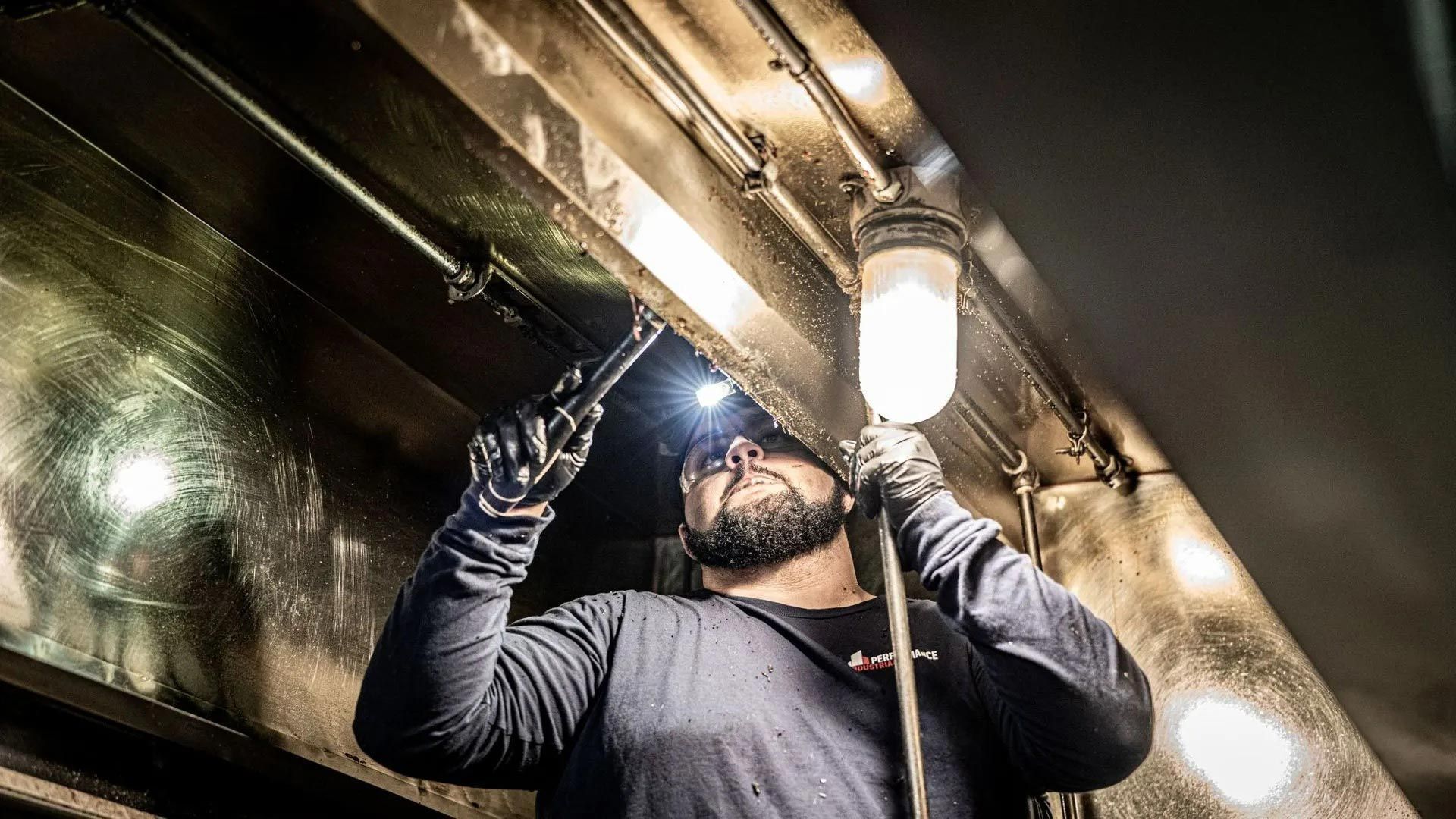 A man is working on a ceiling with a flashlight.