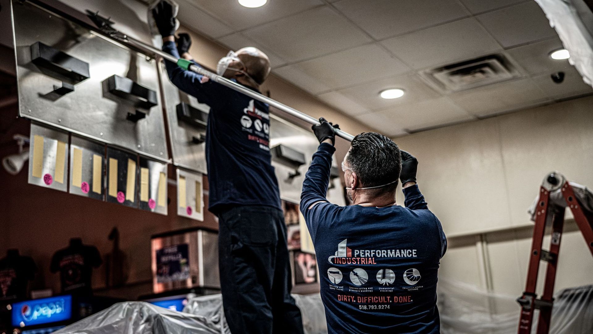 Two men are working on a ceiling in a restaurant.