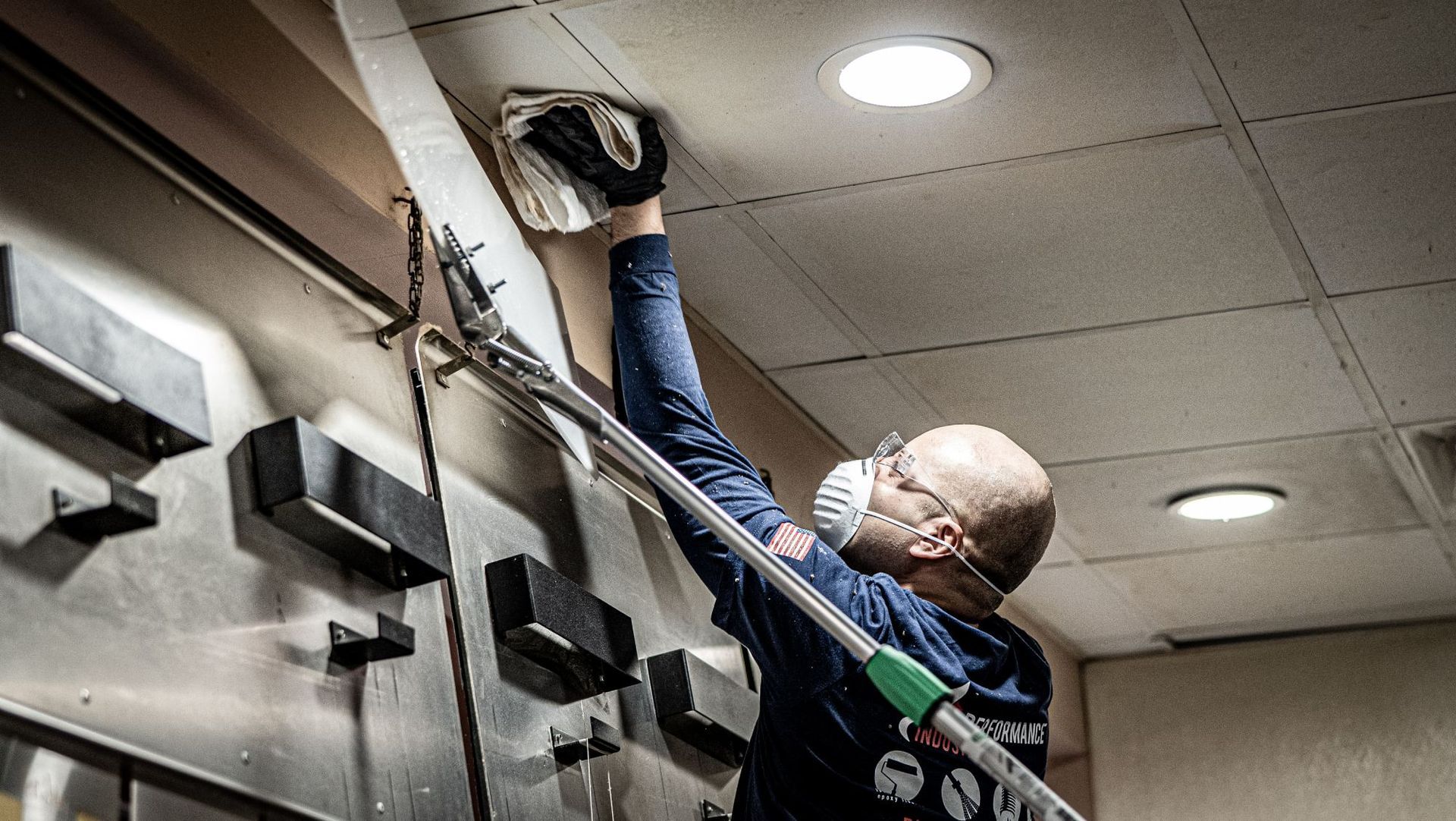 A man wearing a mask and gloves is working on a ceiling.