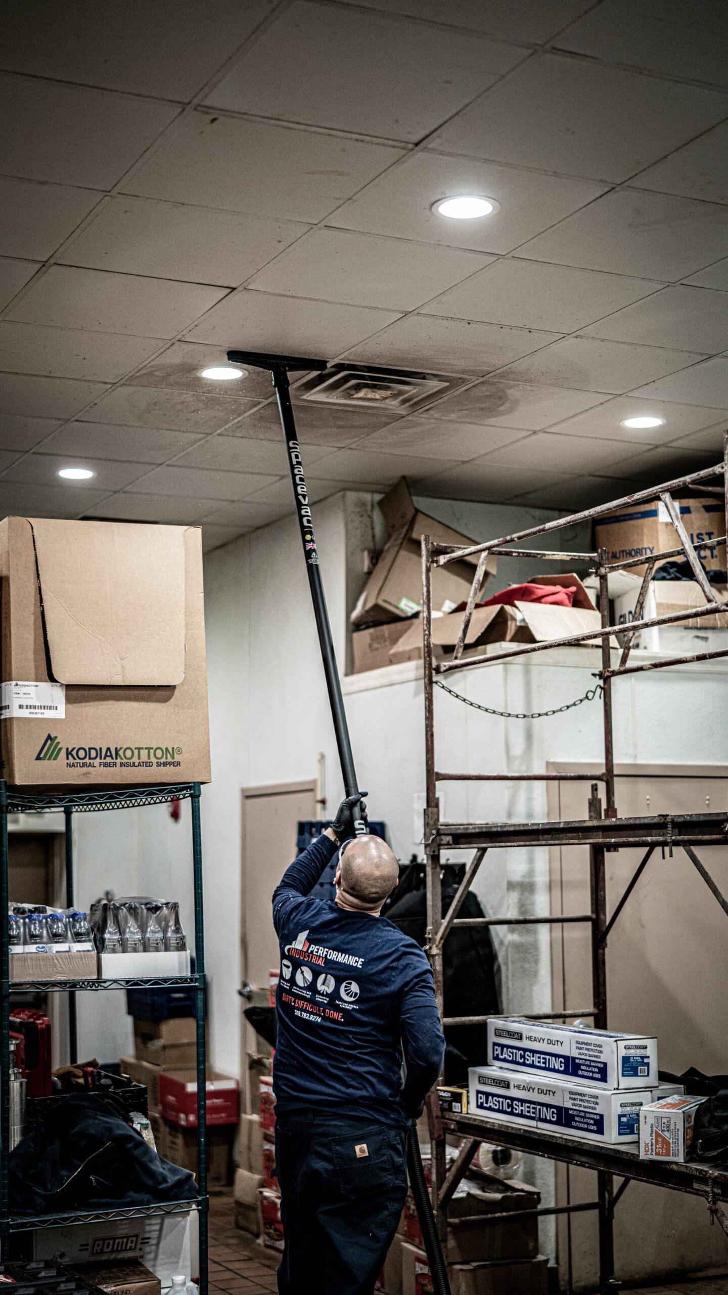 A man is cleaning the ceiling of a building with a mop.