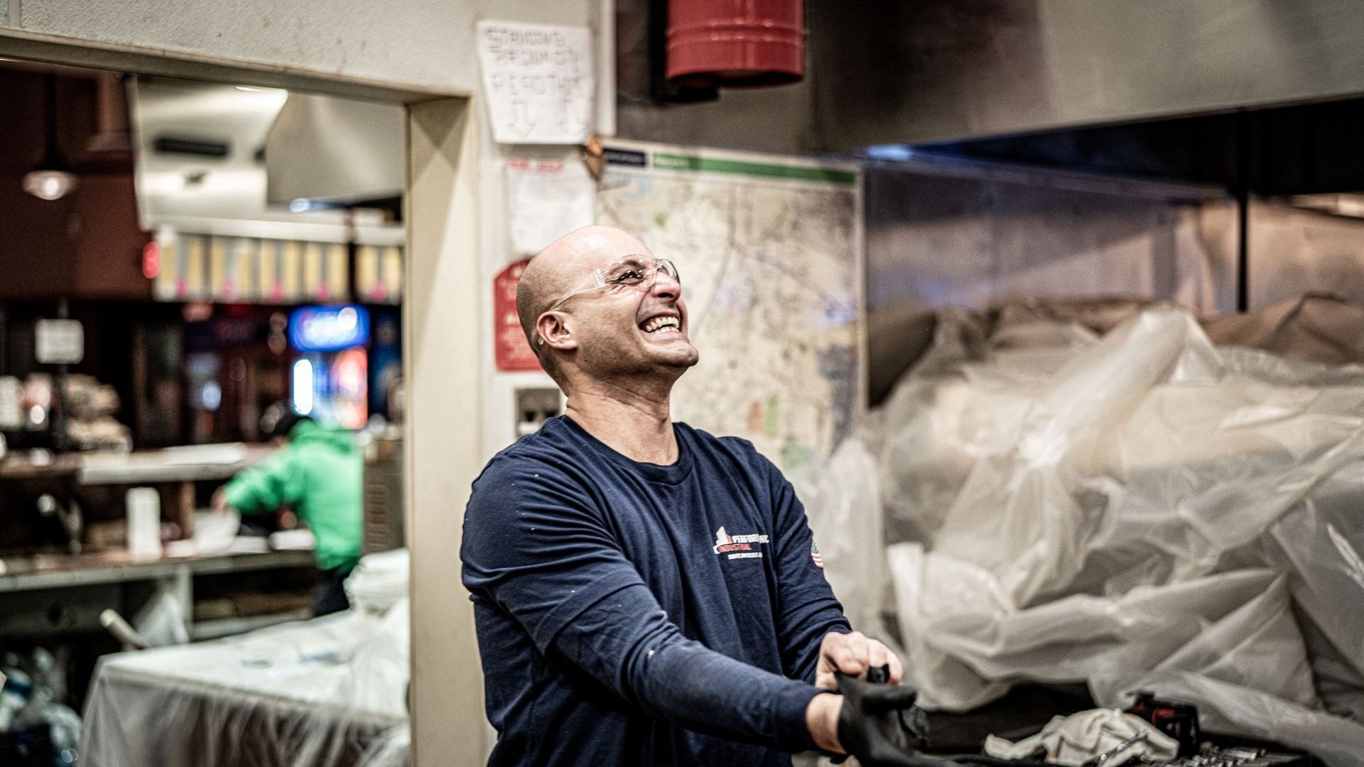 A man is standing in a kitchen laughing.
