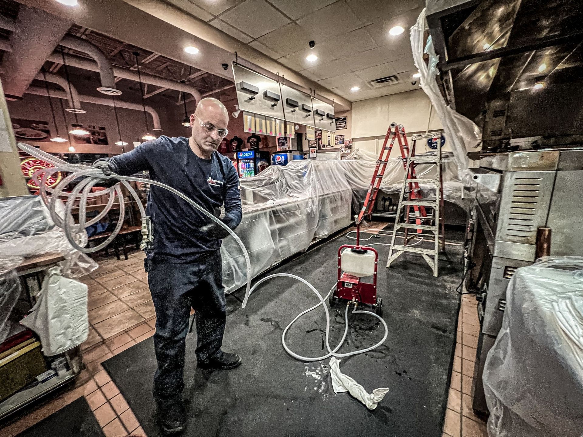 A man is standing in a kitchen holding a hose.