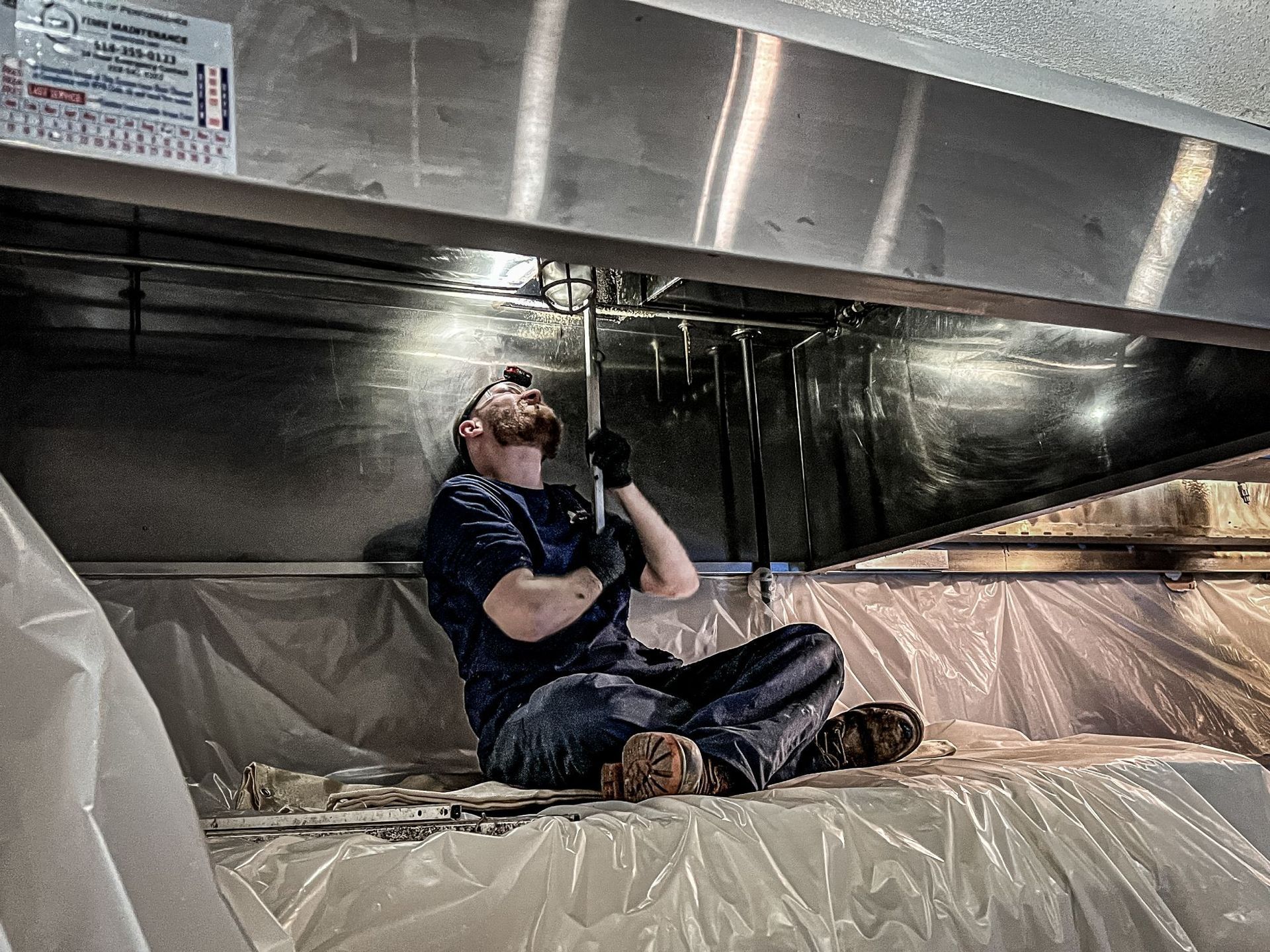 A man is sitting on the ceiling of a building holding a microphone.