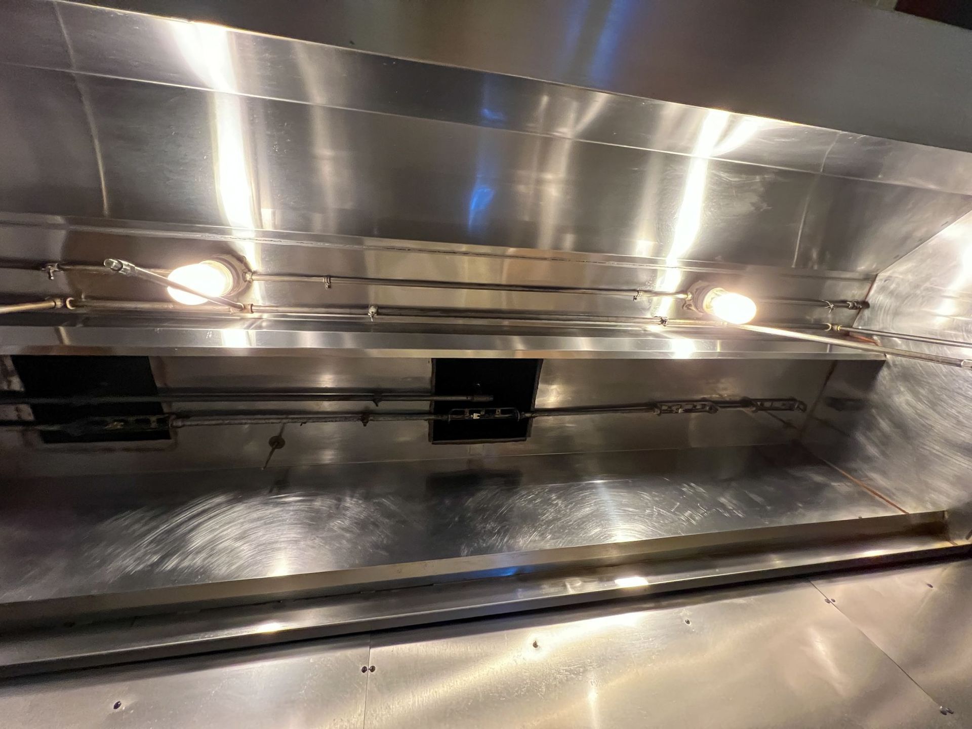 A stainless steel hood with lights hanging from it in a kitchen.